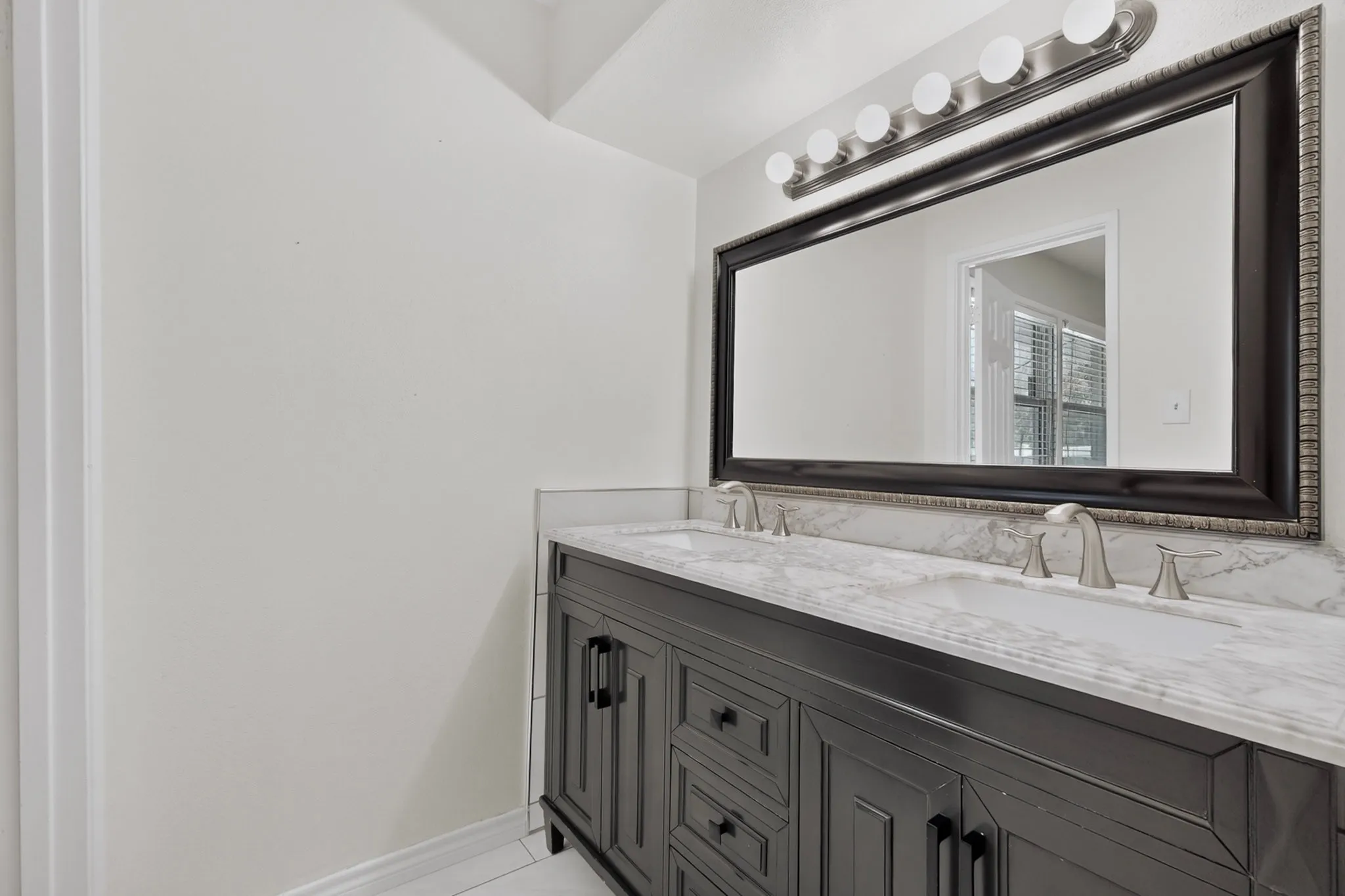 Dual vanity with brushed nickel fixtures, under-mount sinks, and a stone countertop