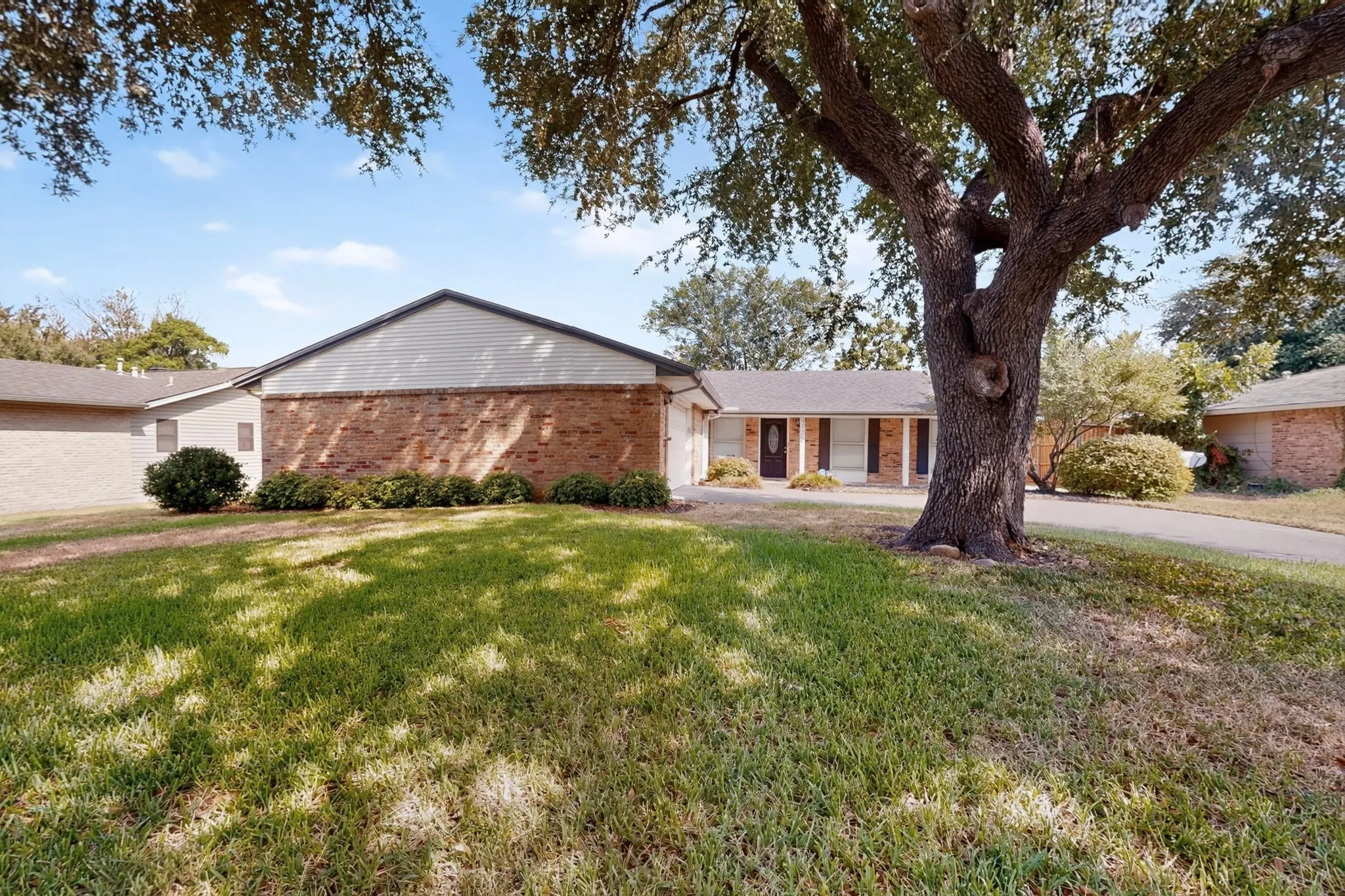 Brick and siding exterior, established front yard landscaping, mature shade tree, concrete driveway, and covered entry