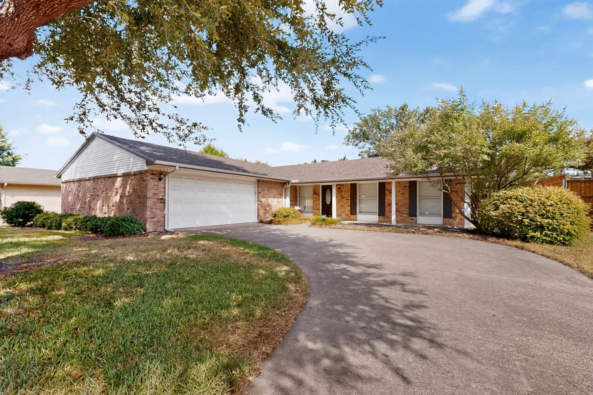 Brick exterior with white siding accents, an attached two-car garage, and a paved driveway