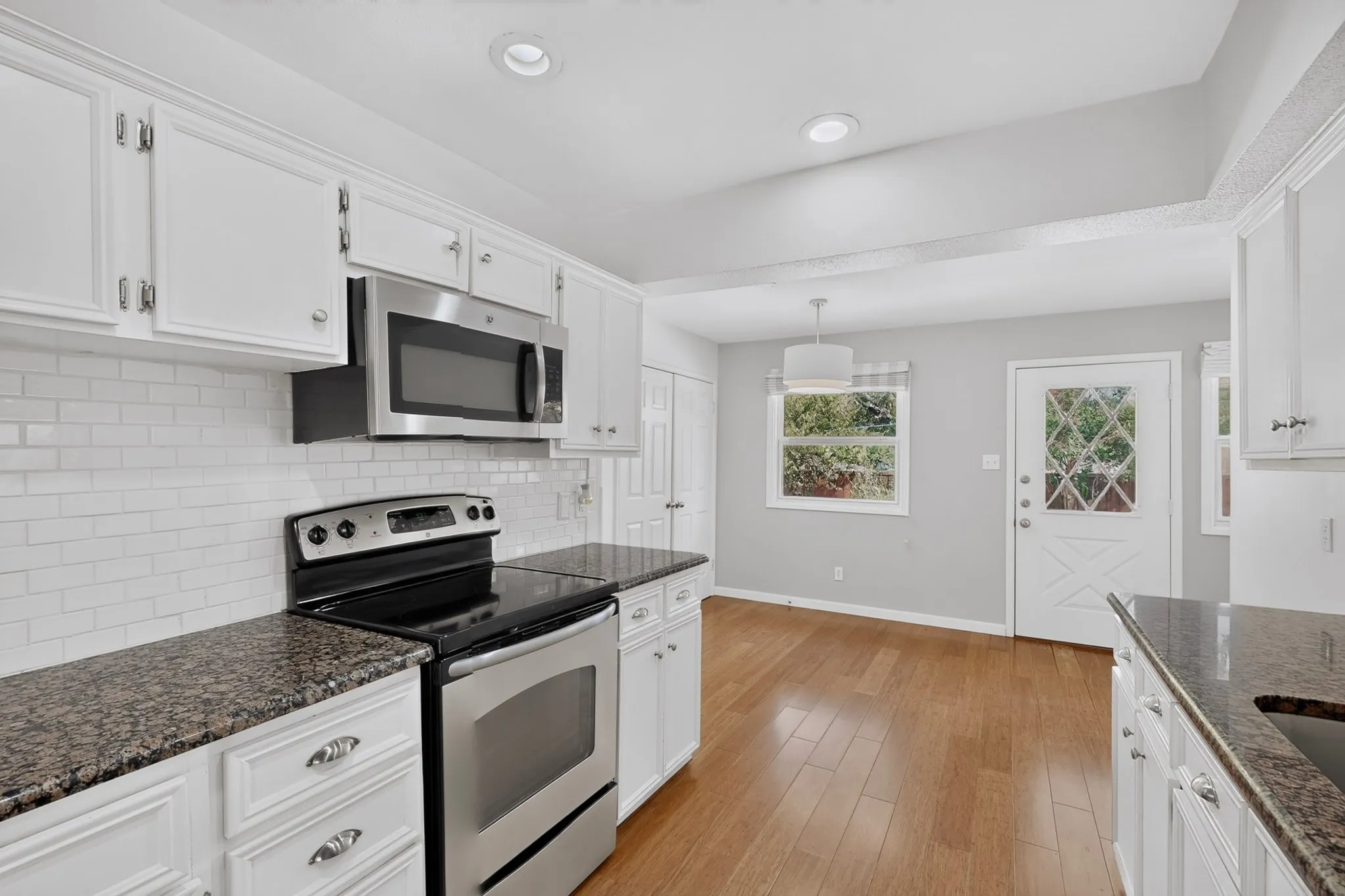 Kitchen featuring white cabinetry, stainless steel appliances, granite countertops, and subway tile backsplash