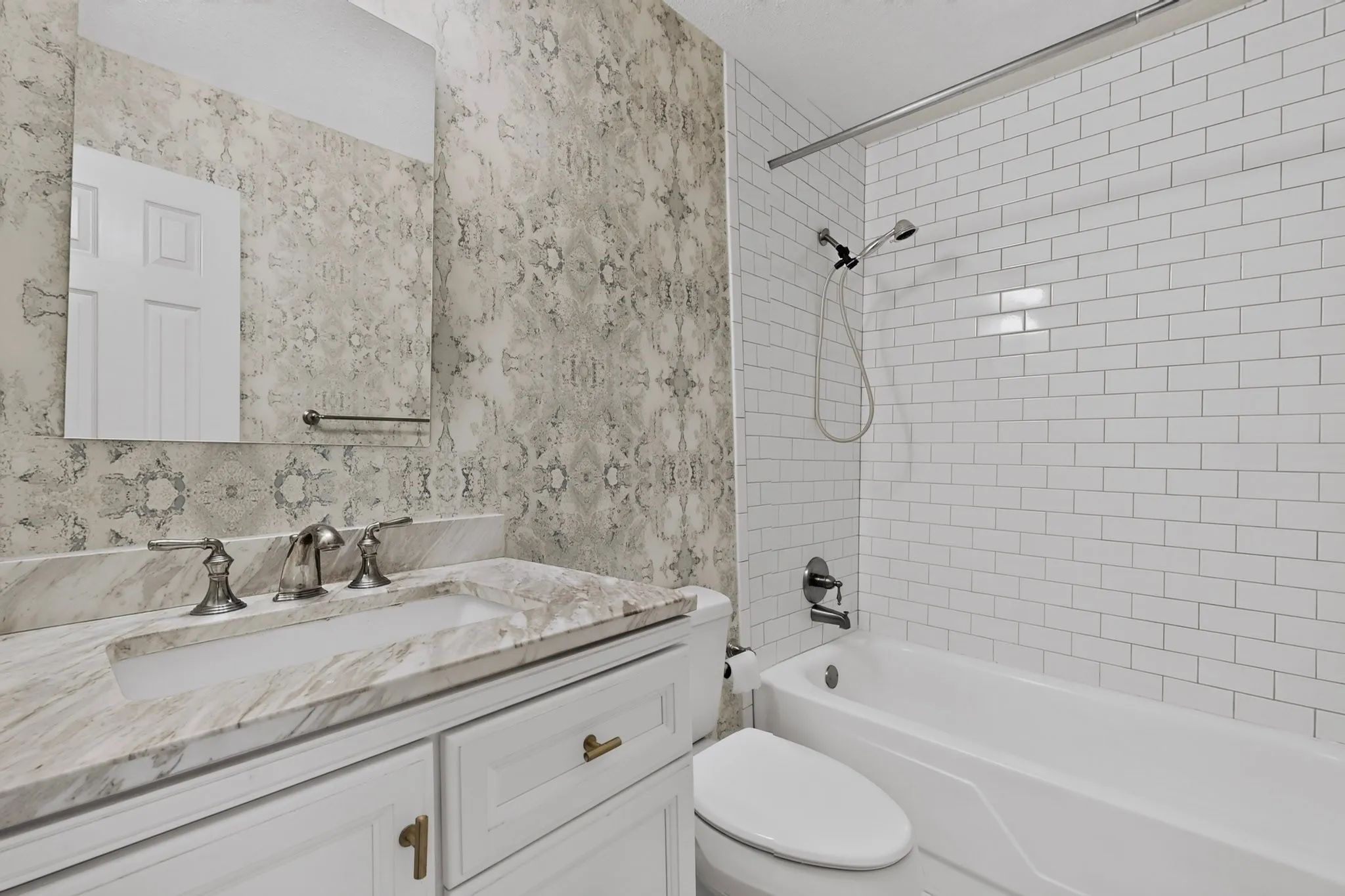White vanity with gold-tone hardware, undermount sink, and stone countertop