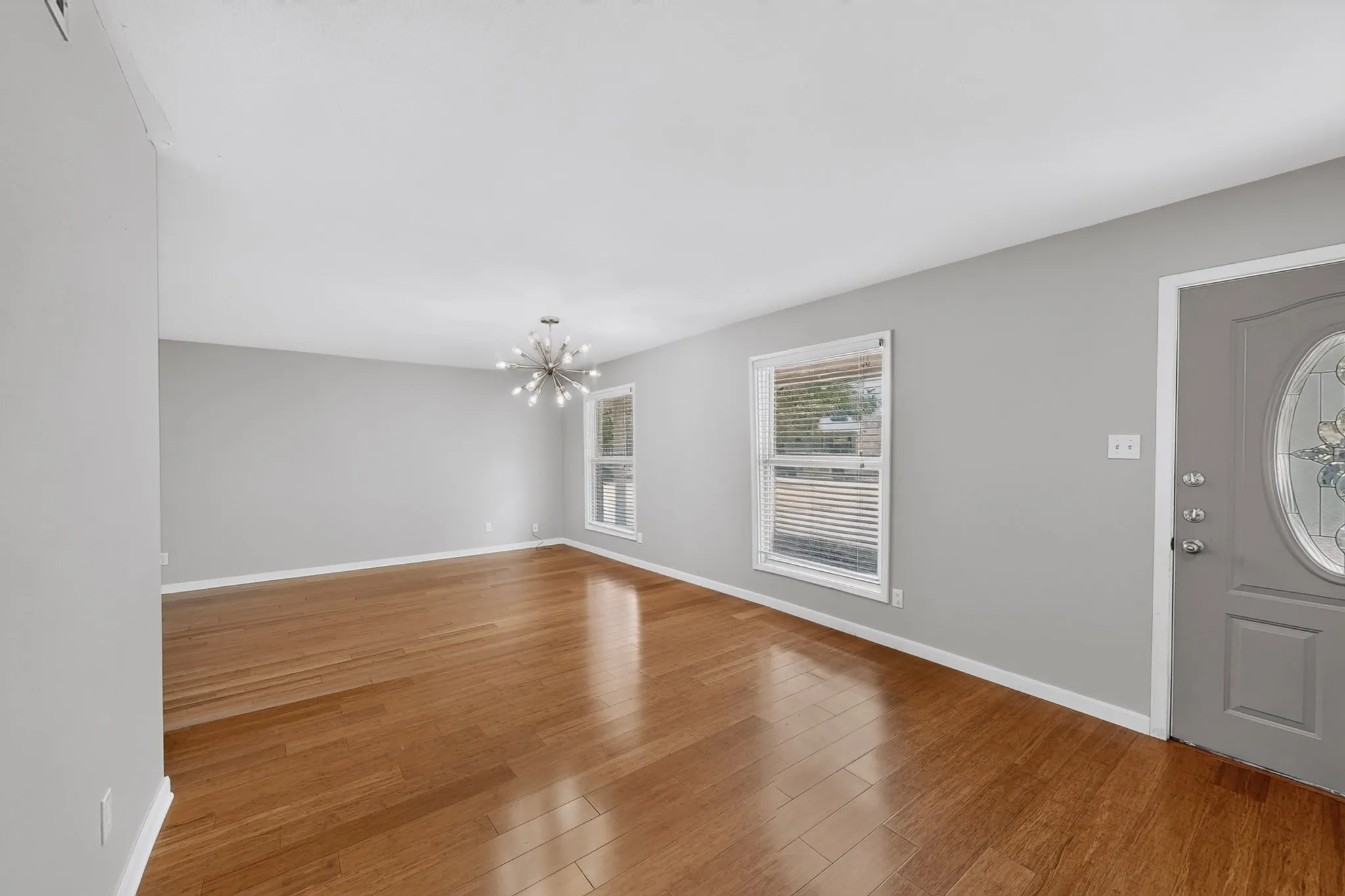 Wood-finish flooring, light grey walls, and a contemporary chandelier