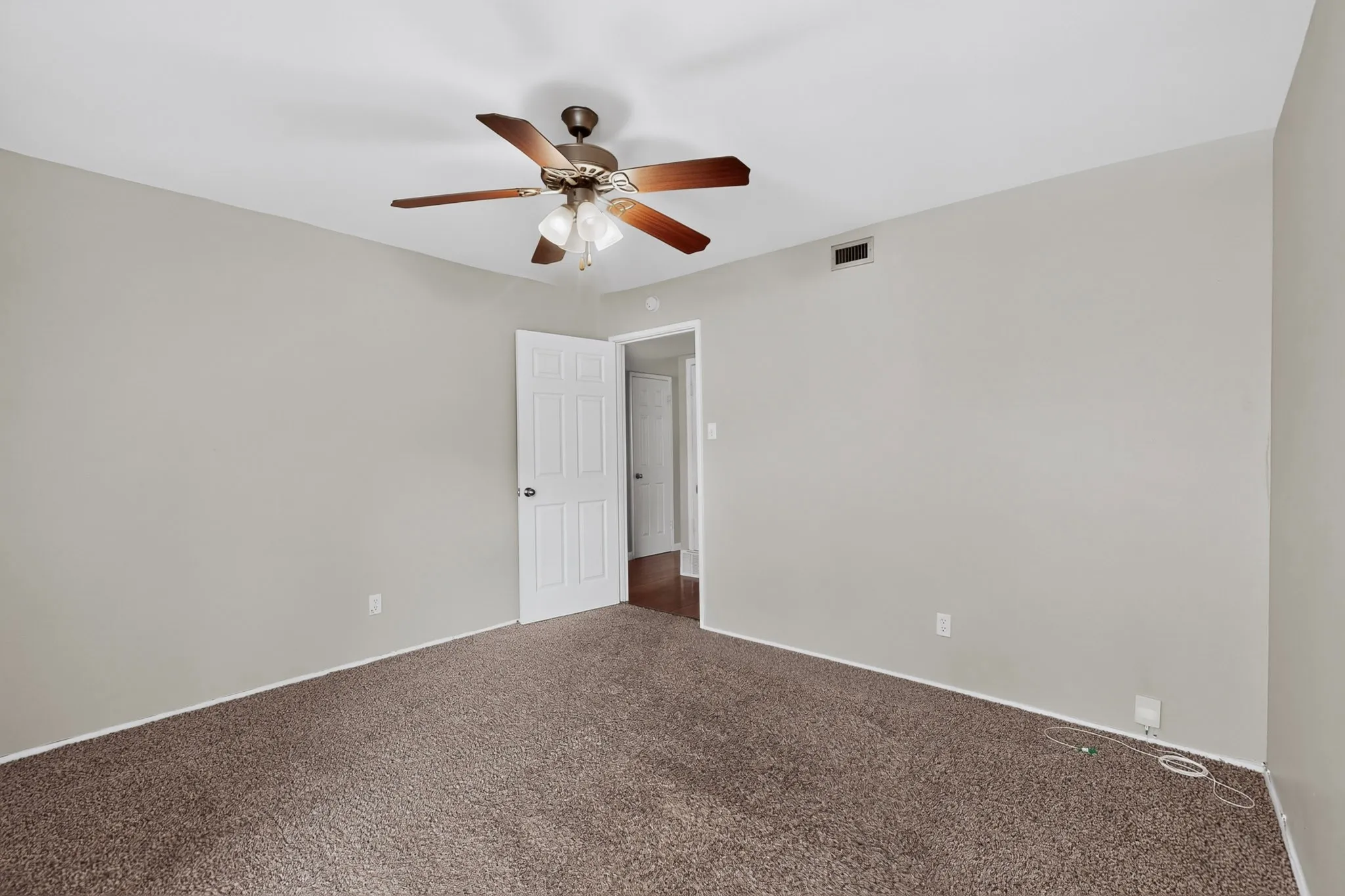 Plush brown carpet, neutral wall paint, and a ceiling fan with light fixture