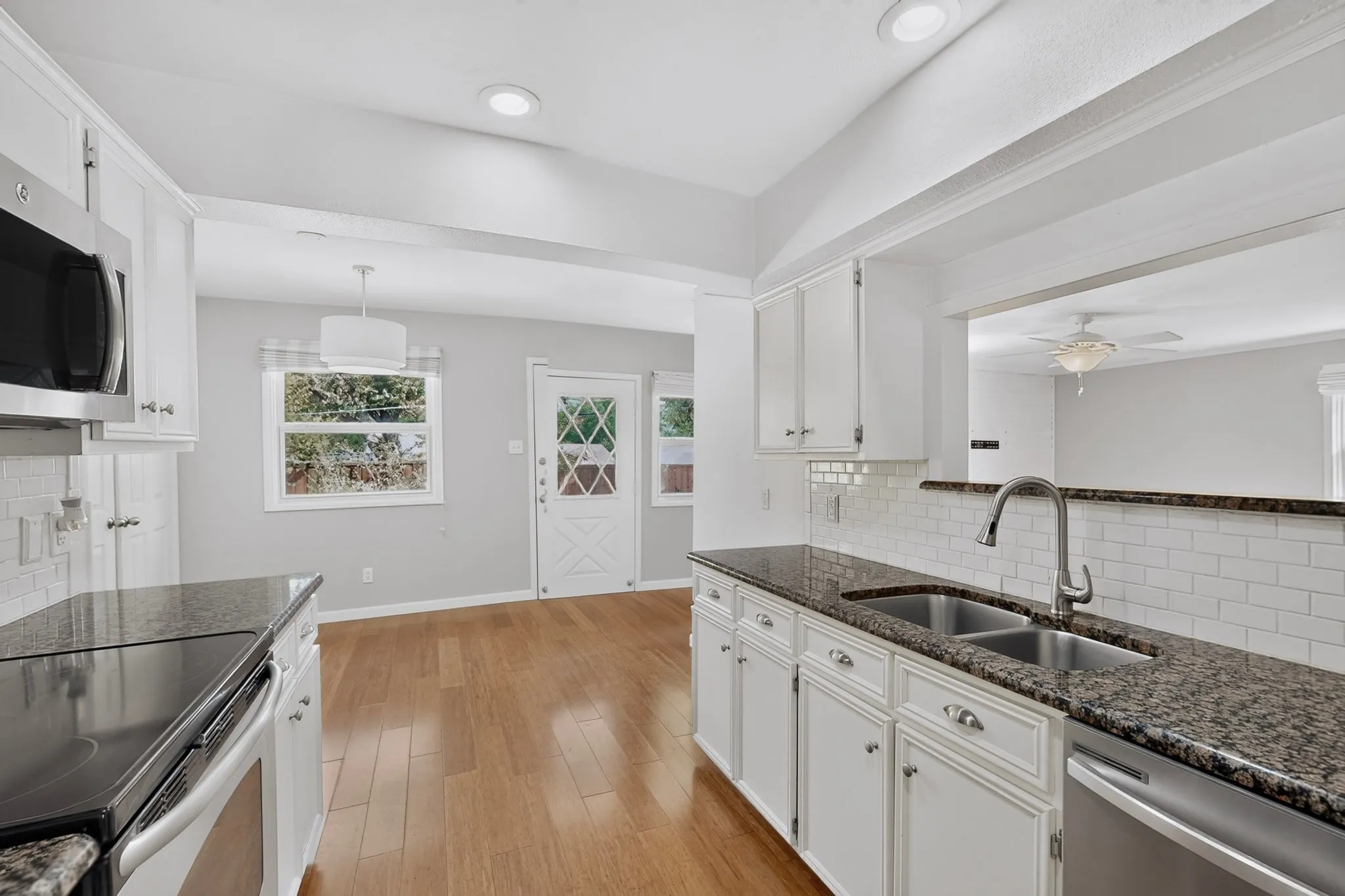Kitchen featuring white cabinetry, dark stone countertops, a subway tile backsplash, and stainless steel appliances