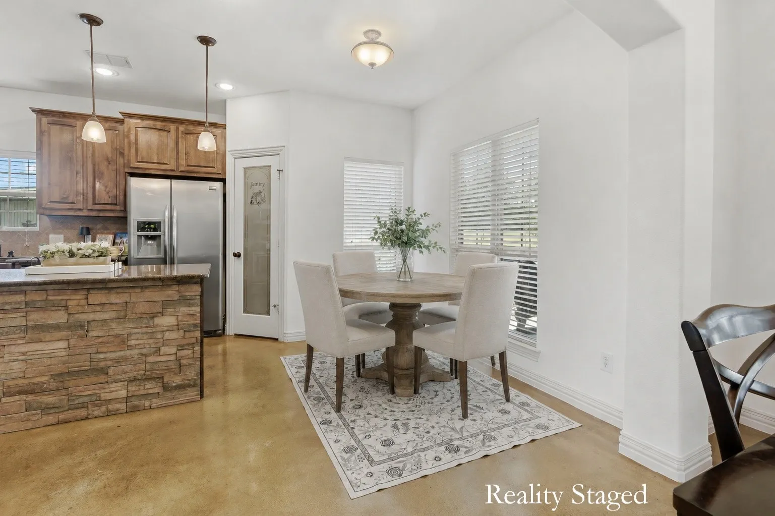 Nestled beside the kitchen just beyond the formal dining room, this bright breakfast nook pairs windows on two sides with warm stained concrete flooring for an inviting spot to enjoy leisurely morning.