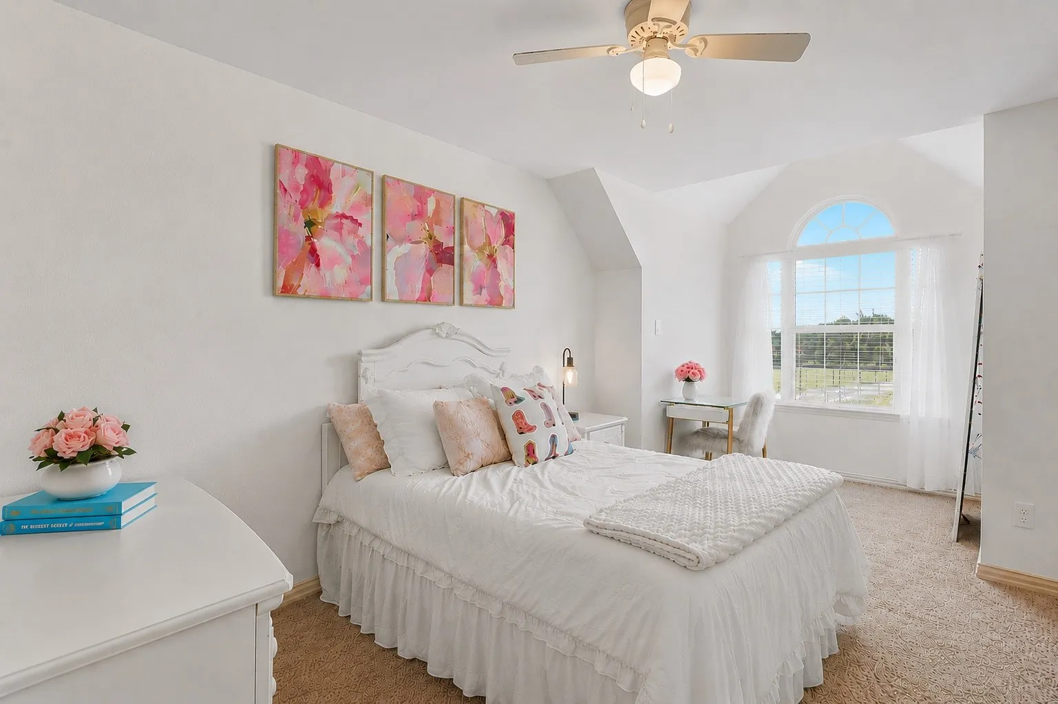 An arched window frames views of the grounds and fills this upstairs bedroom with natural light, highlighting its charming ceiling angles and cozy carpeted interior. Access to the shared Jack and Jill bath and a nearby bonus nook for studying or reading adds everyday convenience to this inviting retreat.