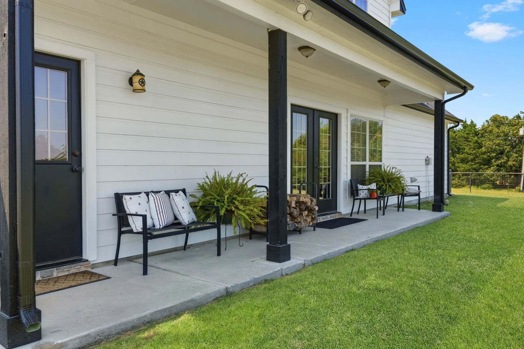Enjoy slow mornings and peaceful evenings on the covered back porch, overlooking the green lawn toward mature trees and the seasonal pond for a relaxing taste of country living.