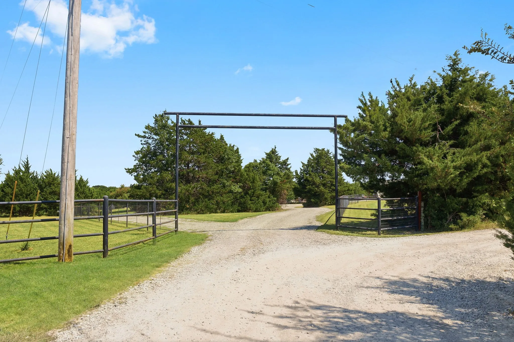 Imagine making this entrance your own with a custom gate and an overhead header bearing your family name or ranch emblem, creating a distinctive welcome along the tree-lined drive.