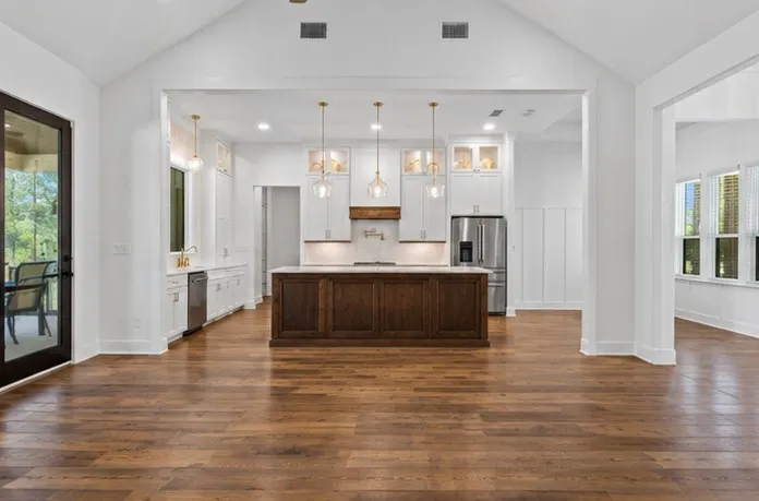 Vaulted ceilings, wood-finish flooring, white cabinetry, dark wood kitchen island, and stainless steel appliances
