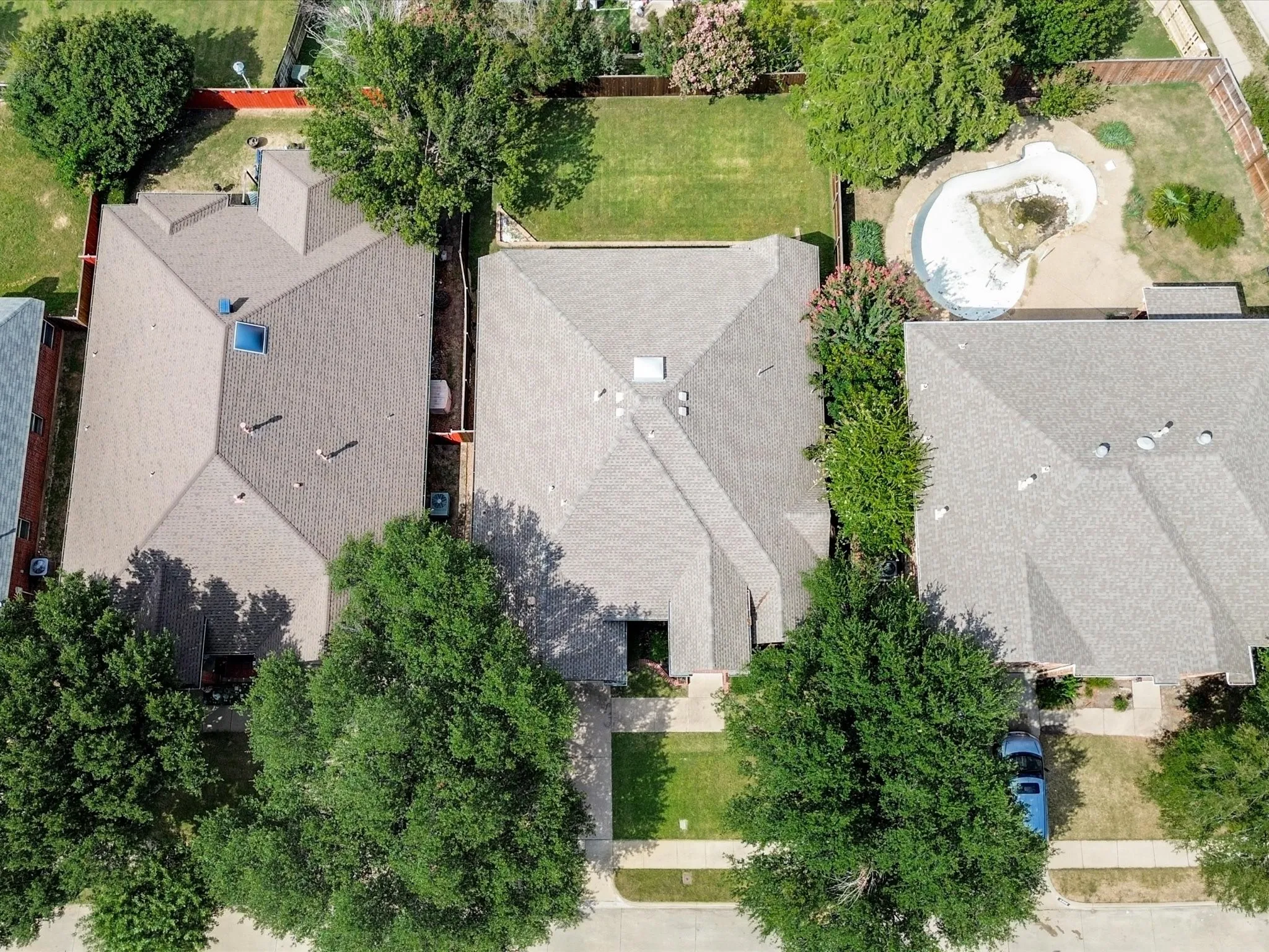 Aerial view showcasing two substantial residences with architectural asphalt shingle roofing, manicured lawns, and mature landscaping throughout the surrounding grounds