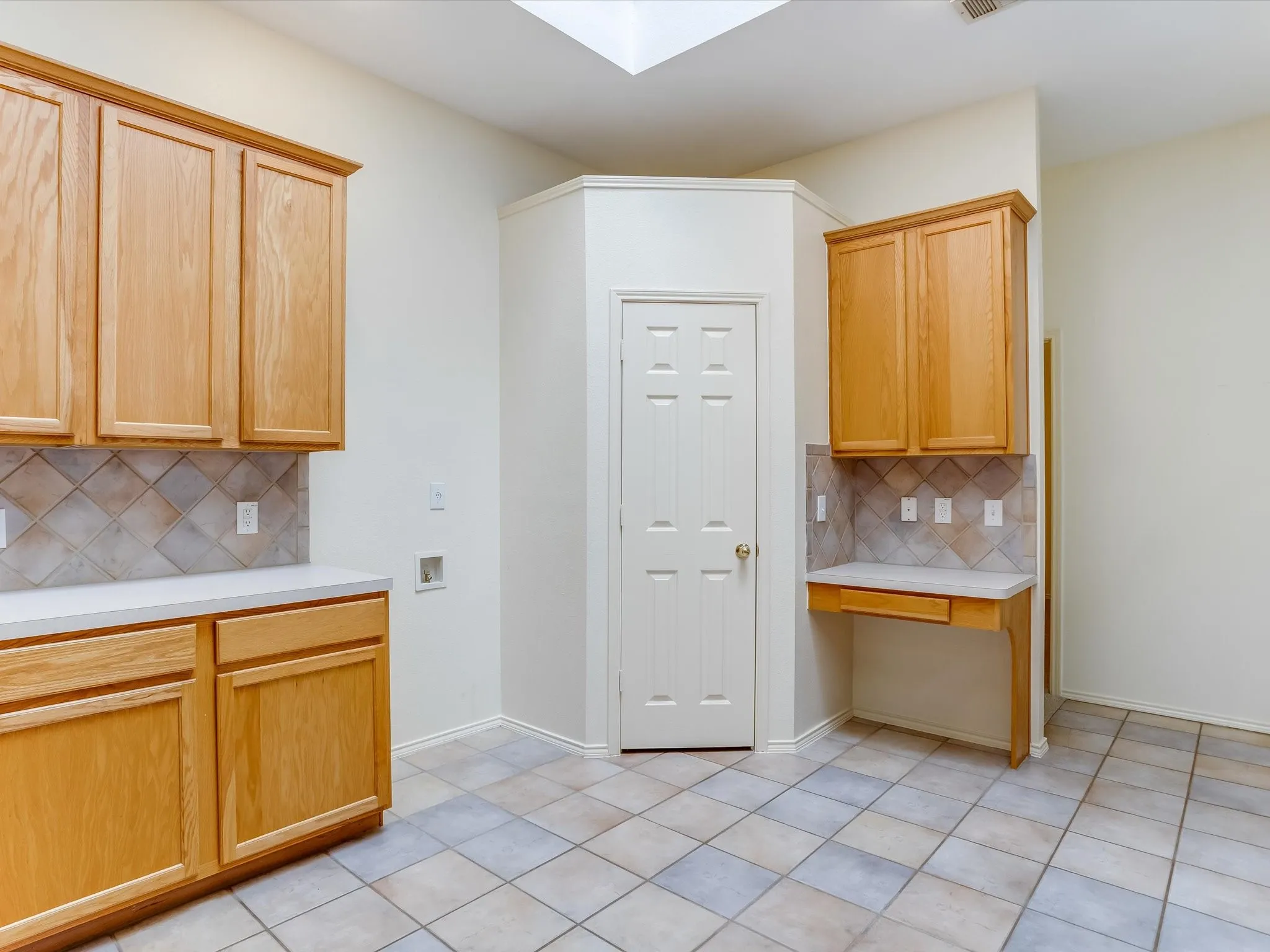 Spacious kitchen featuring wood-finish cabinetry, ceramic tile flooring, and a convenient pantry closet with six-panel door
