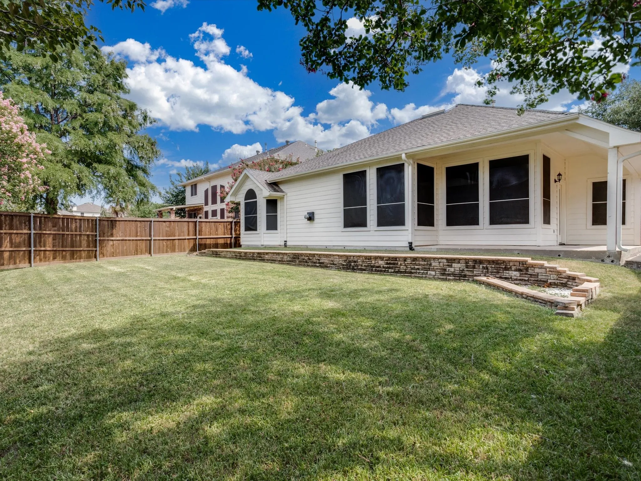 Spacious backyard with manicured lawn and mature shade trees, backing the home's rear elevation