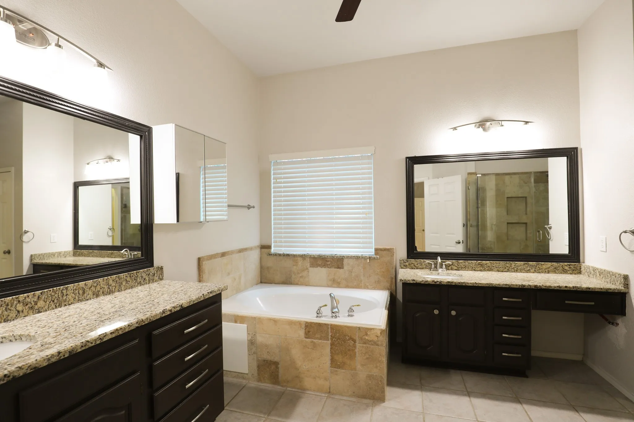 Dual vanity sinks with granite countertops and dark wood-finish cabinetry