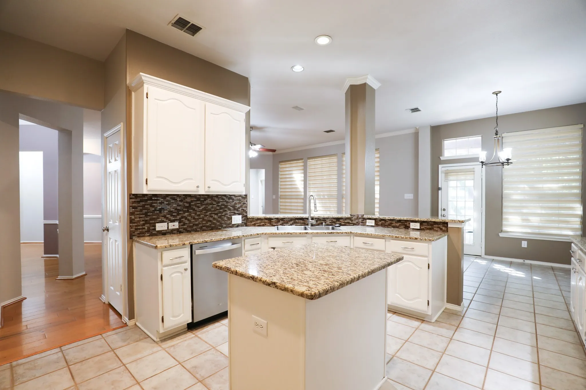 Kitchen featuring white cabinetry, granite countertops, tile flooring, and a mosaic tile backsplash