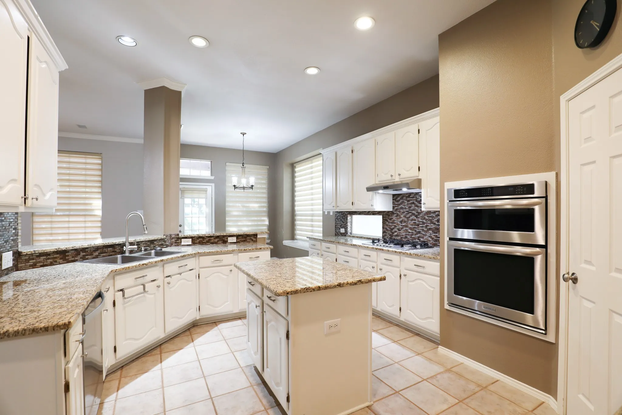 Kitchen featuring white cabinetry, granite countertops, tile flooring, a center island, and stainless steel built-in double ovens