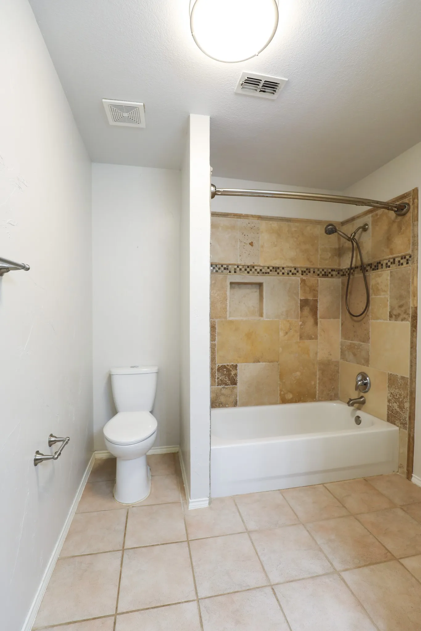 Bathtub with tiled surround, integrated shower niche, and mosaic accent