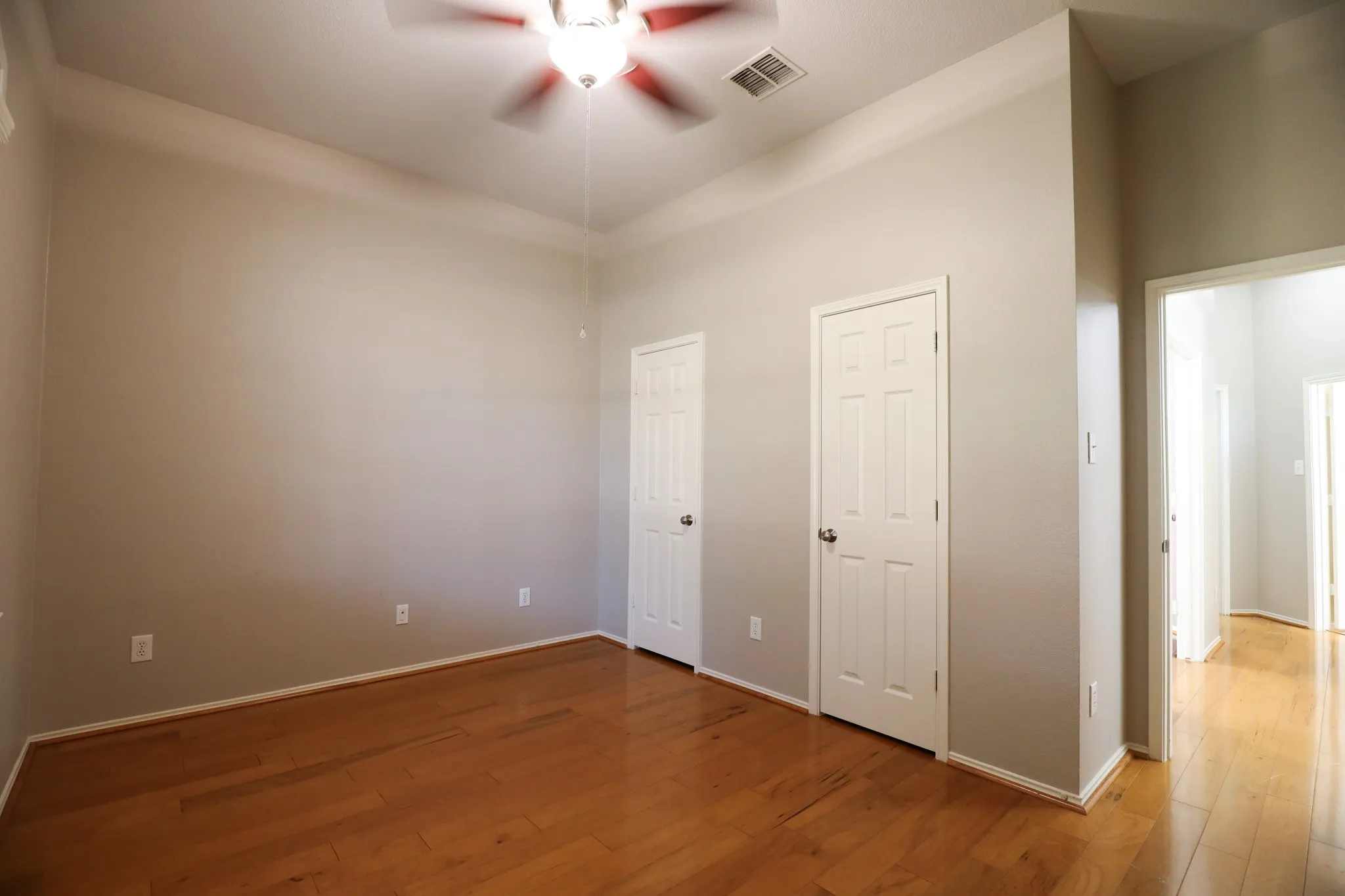 Hardwood-style flooring, tray ceiling, ceiling fan, and white paneled doors