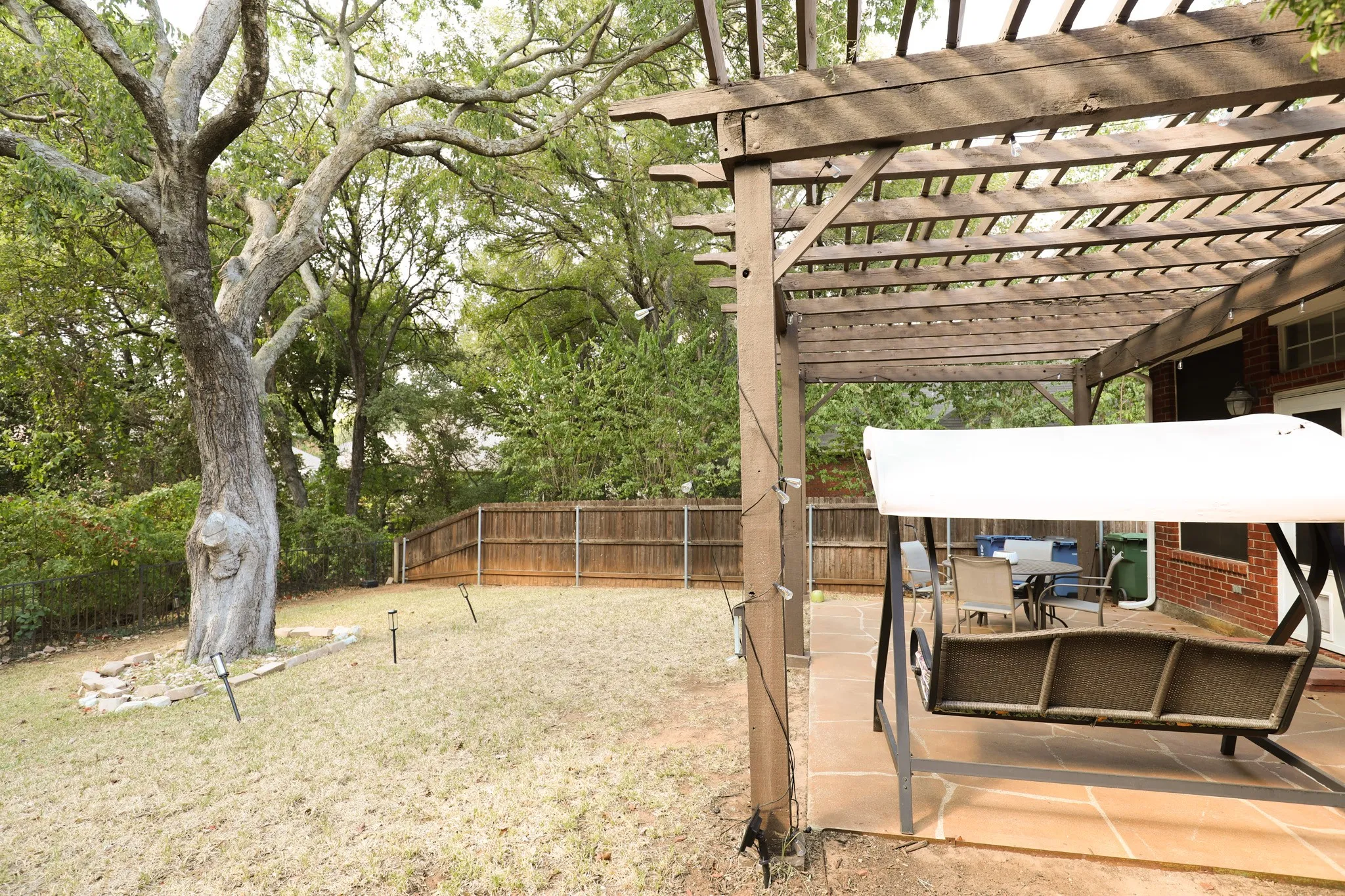 Expansive backyard featuring a mature tree, wood privacy fencing, and a brick-detailed exterior