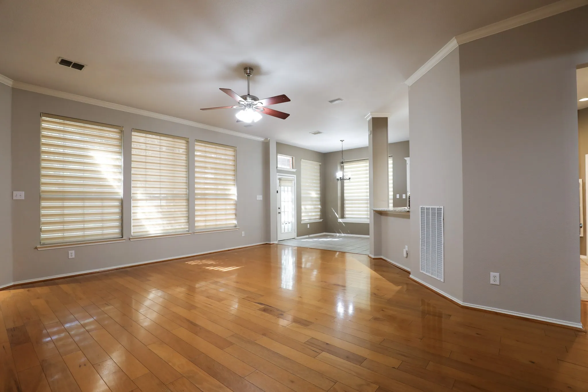Hardwood flooring, multiple windows with blinds, ceiling fan with integrated lighting, crown molding, and recessed lighting