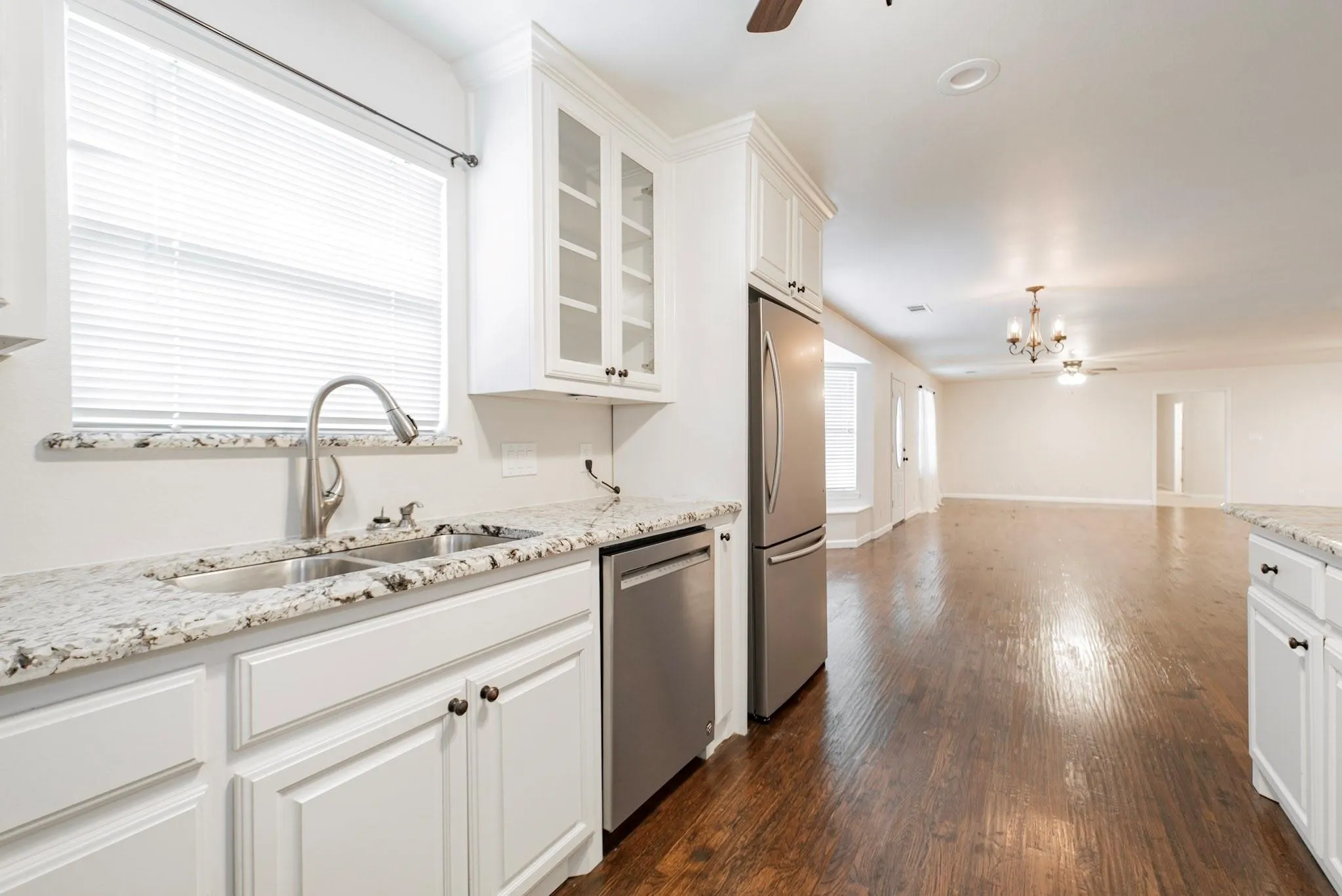 Kitchen featuring white cabinetry, stainless steel appliances, granite countertops, and a double basin sink with a gooseneck faucet