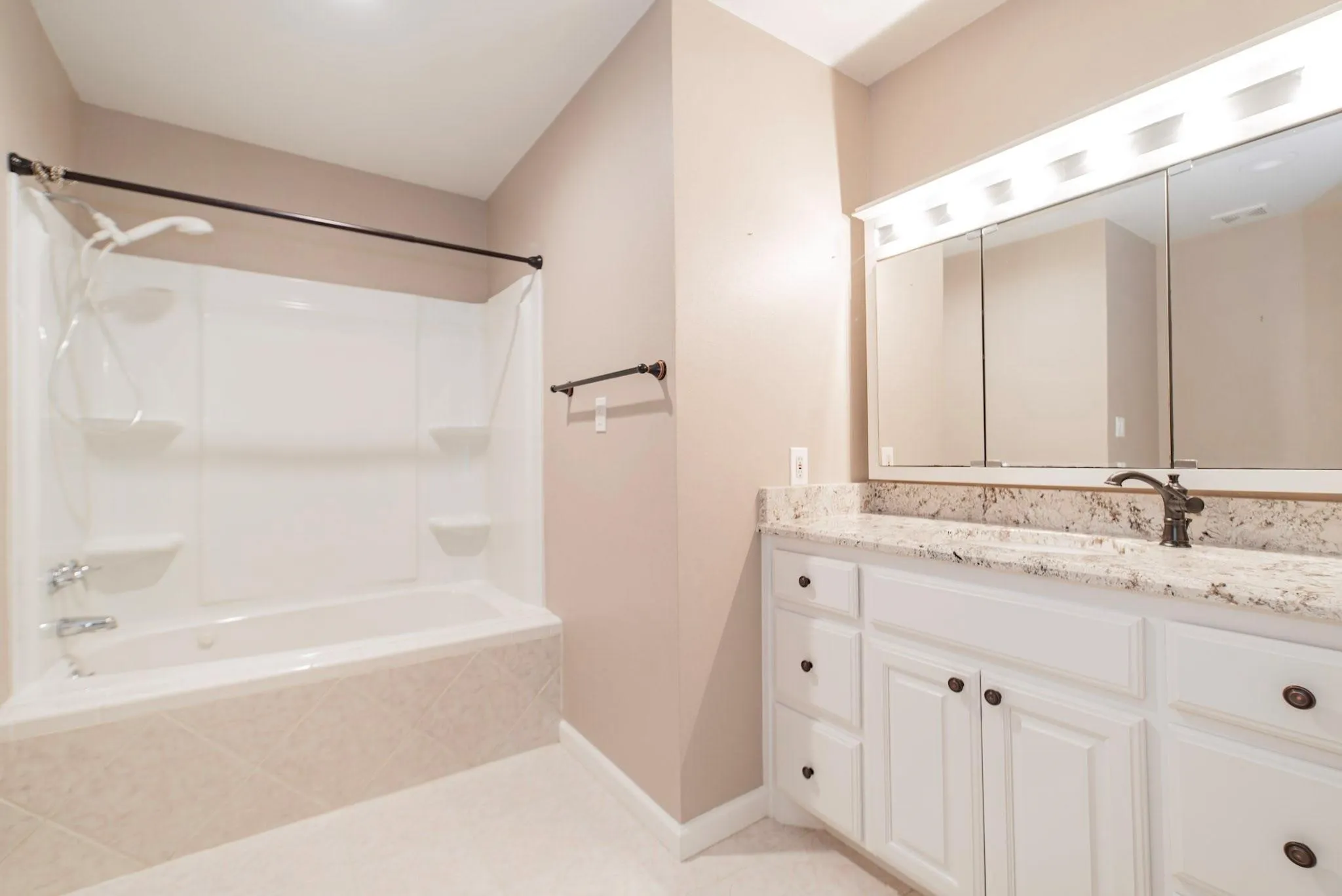 Bathroom featuring a white vanity with a light-colored countertop, an integrated sink with an oil-rubbed bronze faucet, and a large medicine cabinet mirror with overhead lighting