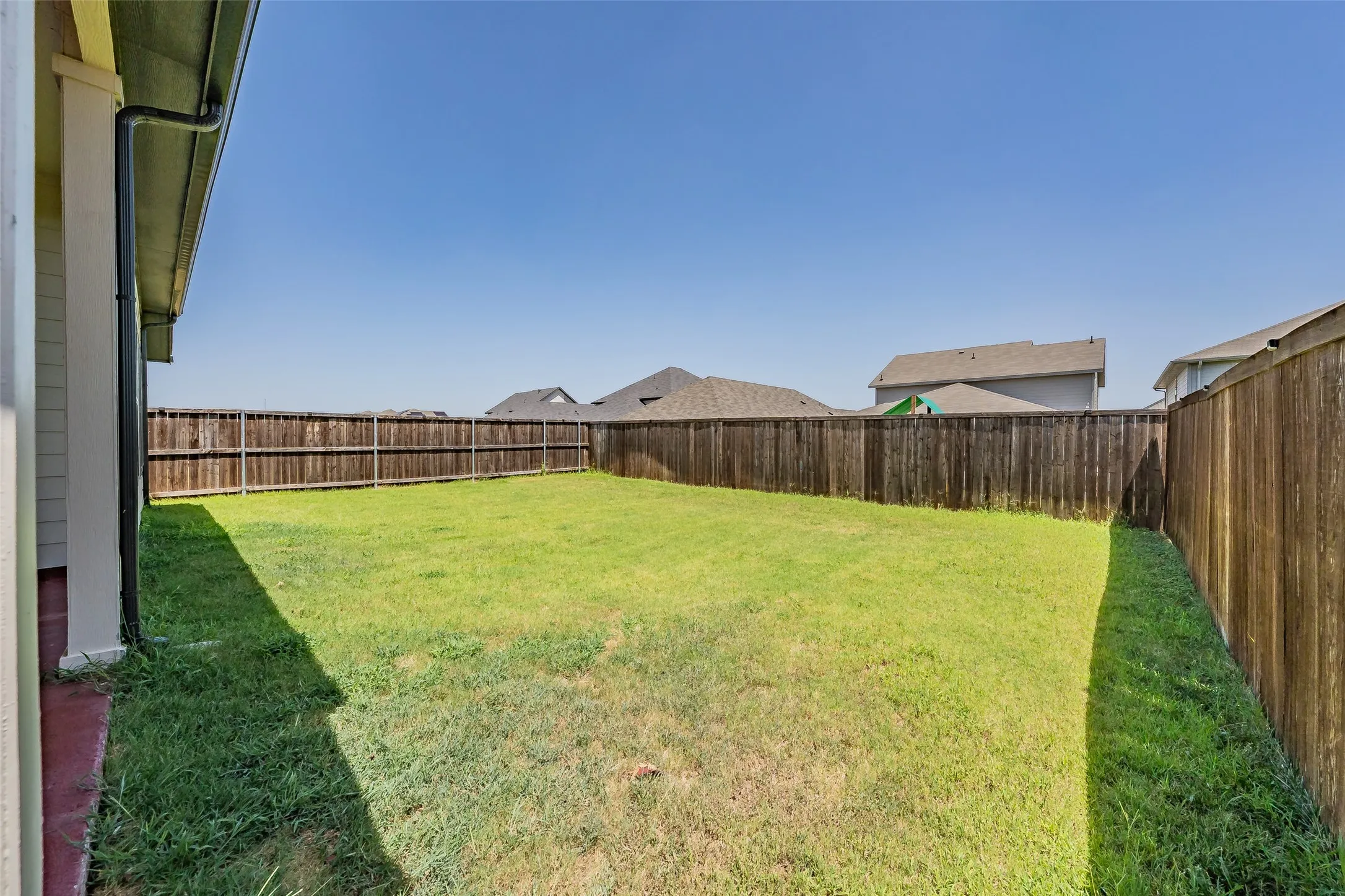 Expansive backyard featuring a lush lawn and a full perimeter wood privacy fence