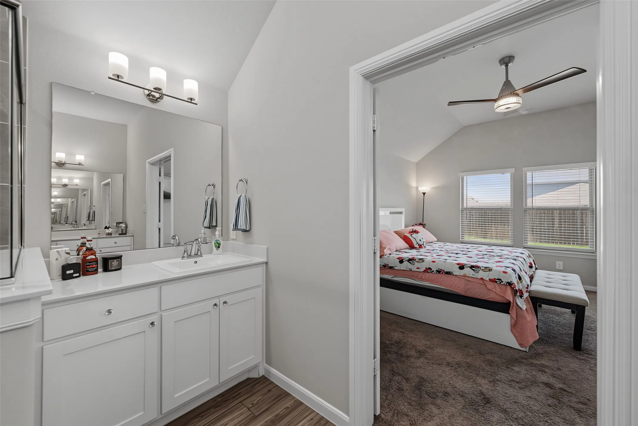 White vanity with an integrated sink and wood-finish flooring