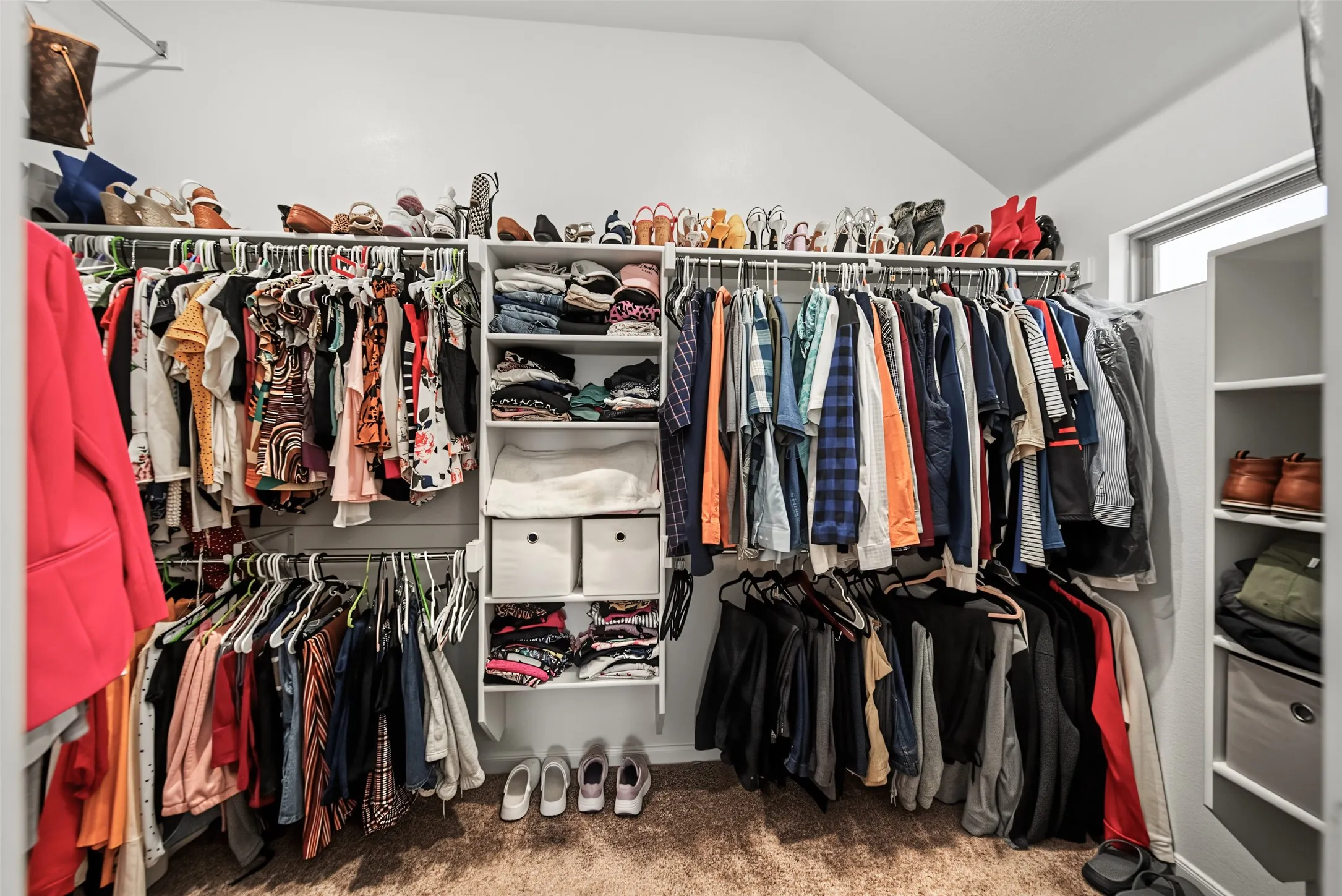 Custom closet system with multiple hanging rods, integrated shelving, and sloped ceiling