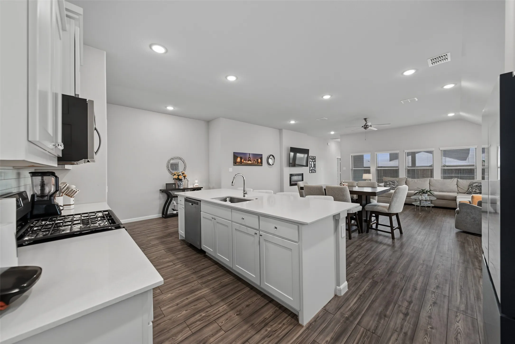 Spacious open-concept living area featuring wood-finish flooring, recessed lighting, and vaulted ceilings