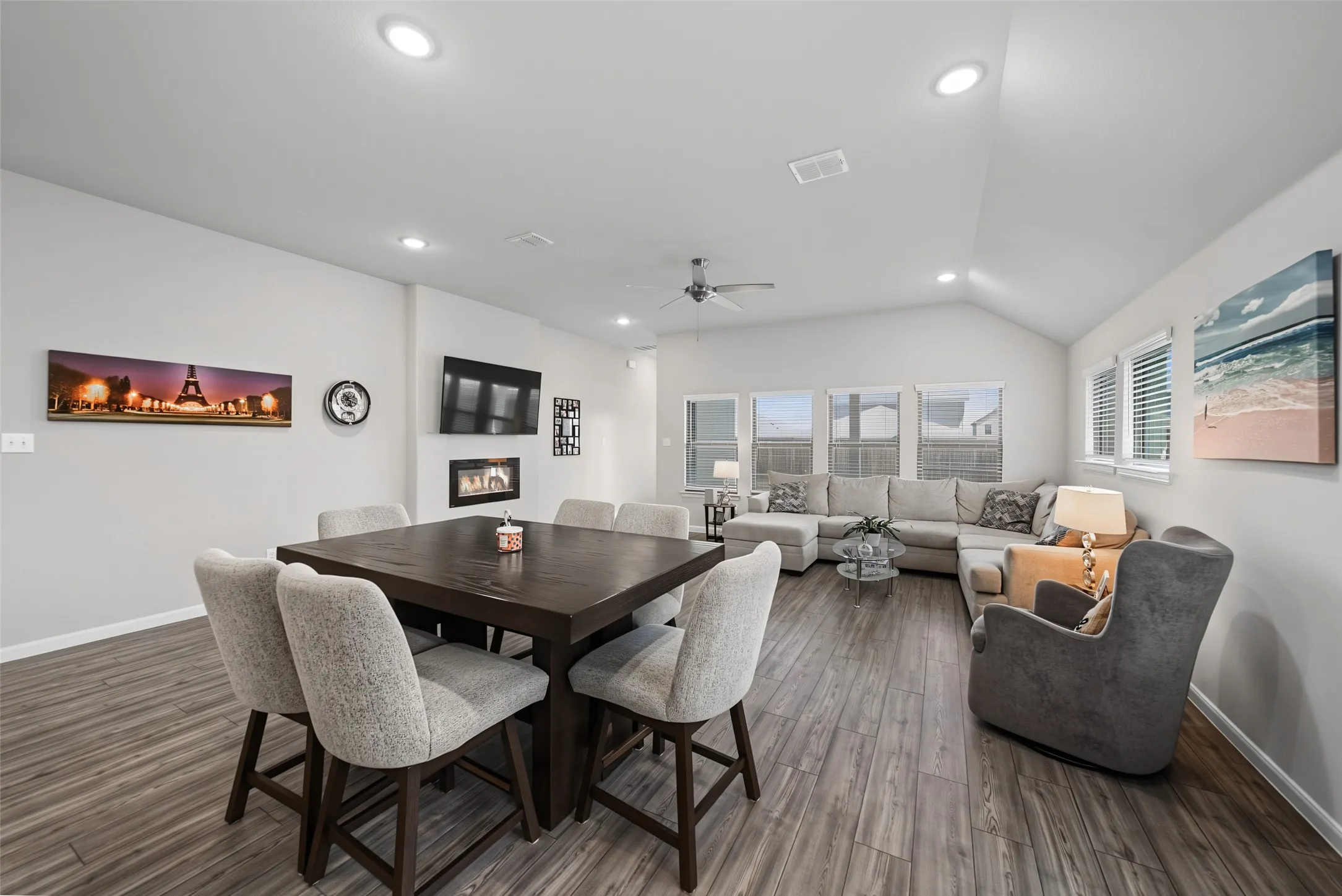 Vaulted ceiling with recessed lighting, wood-finish flooring, multiple windows, and a built-in wall fireplace