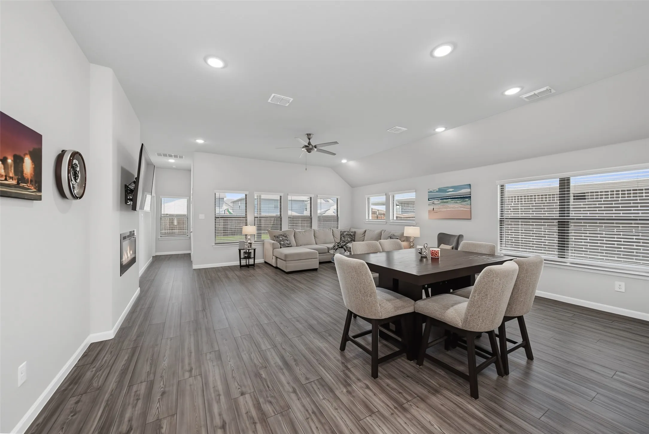 Vaulted ceilings with recessed lighting, wood-finish flooring, multiple windows with blinds, and a built-in fireplace