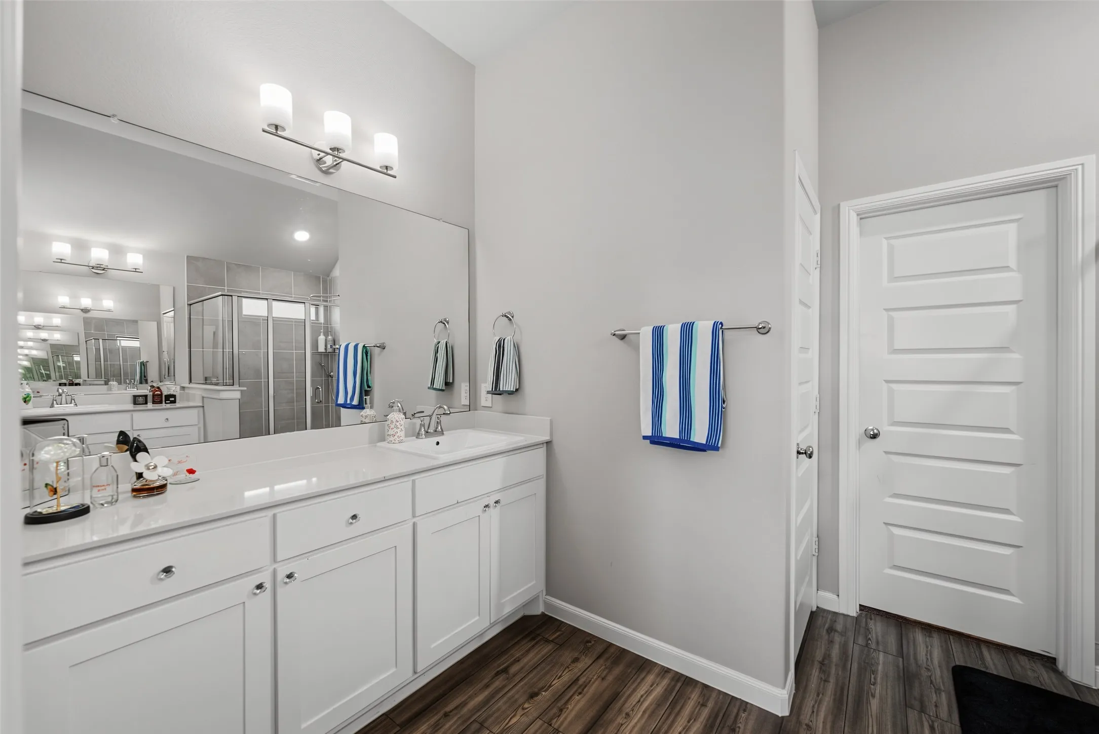 Dual vanity with white cabinetry, integrated sinks, chrome fixtures, and a large wall-mounted mirror