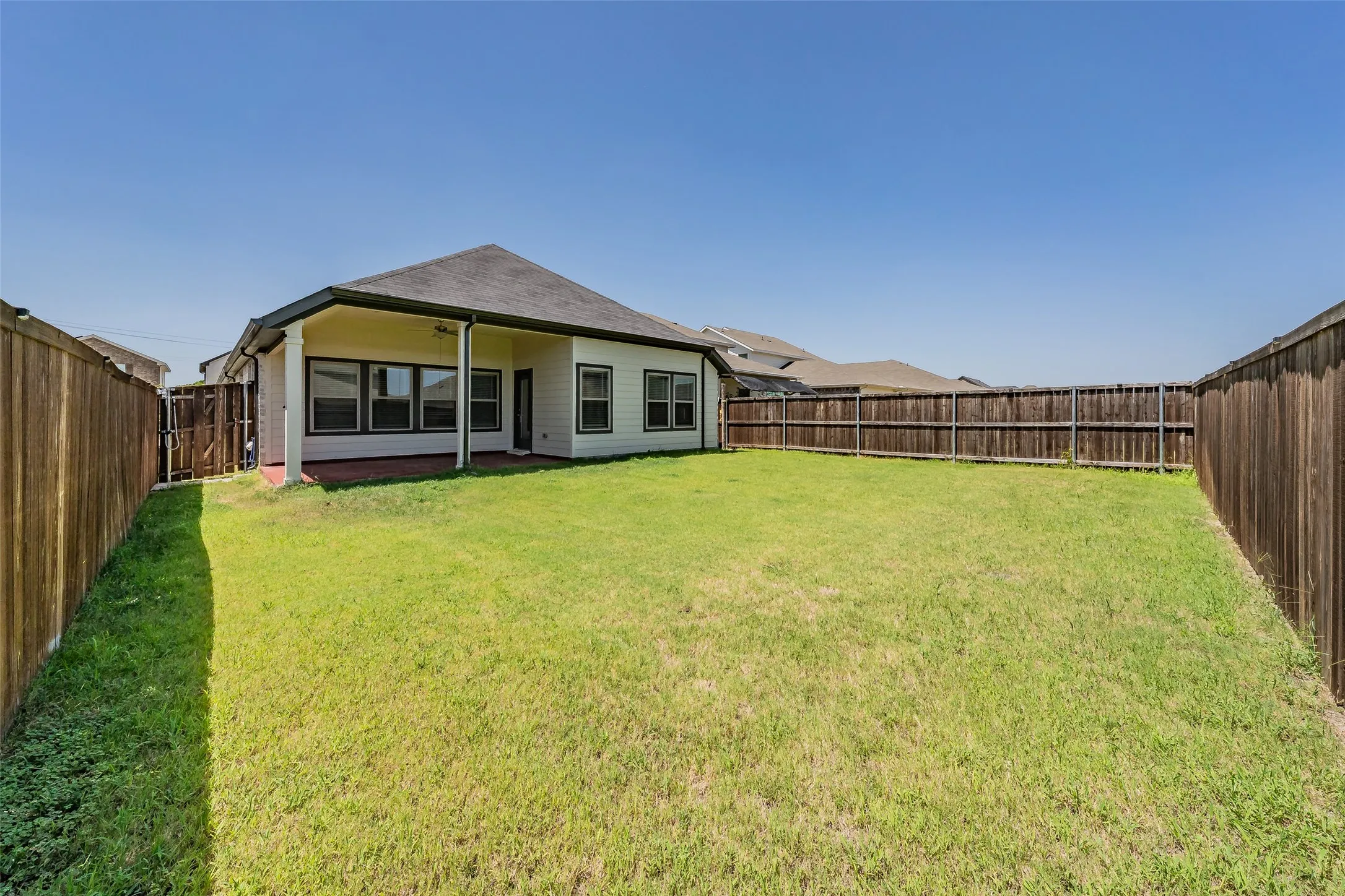 Expansive grassy yard area with perimeter fencing