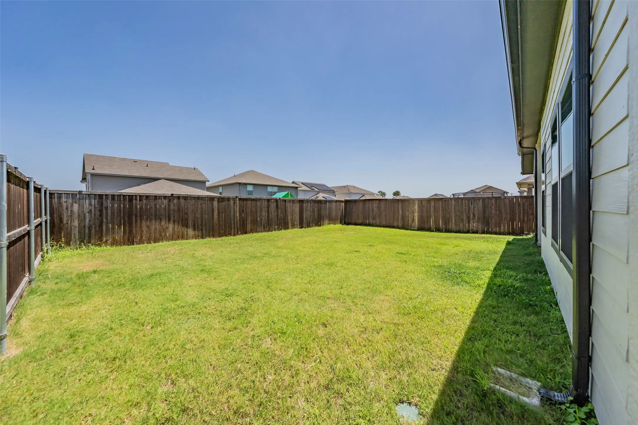 Expansive grass lawn bordered by a wood privacy fence