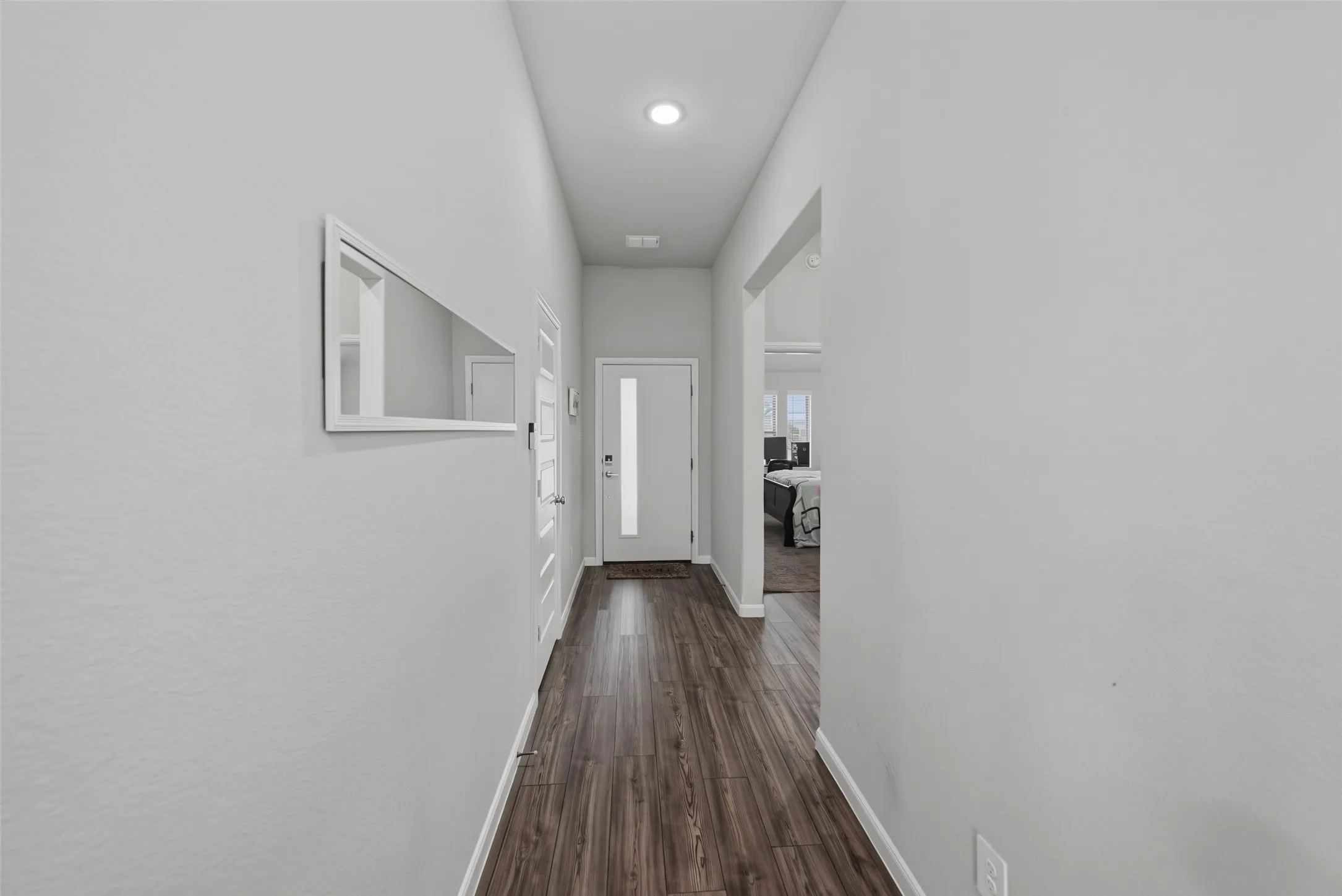Recessed lighting illumination, wood-finish flooring, light-toned wall finishes, white interior doors, and a front entry door with a frosted glass insert