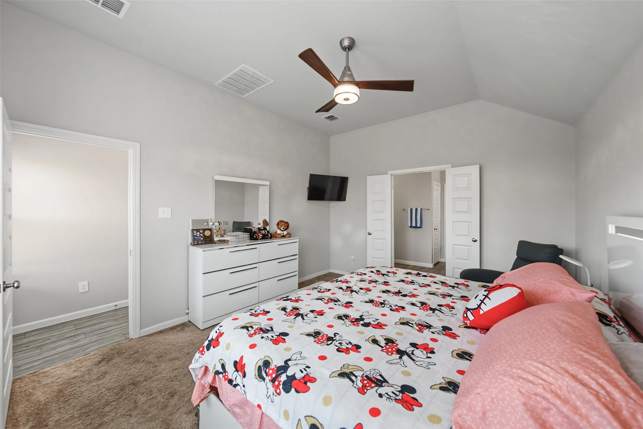 Vaulted ceiling, ceiling fan with integrated lighting, neutral wall color, carpet flooring, interior doors with panel details