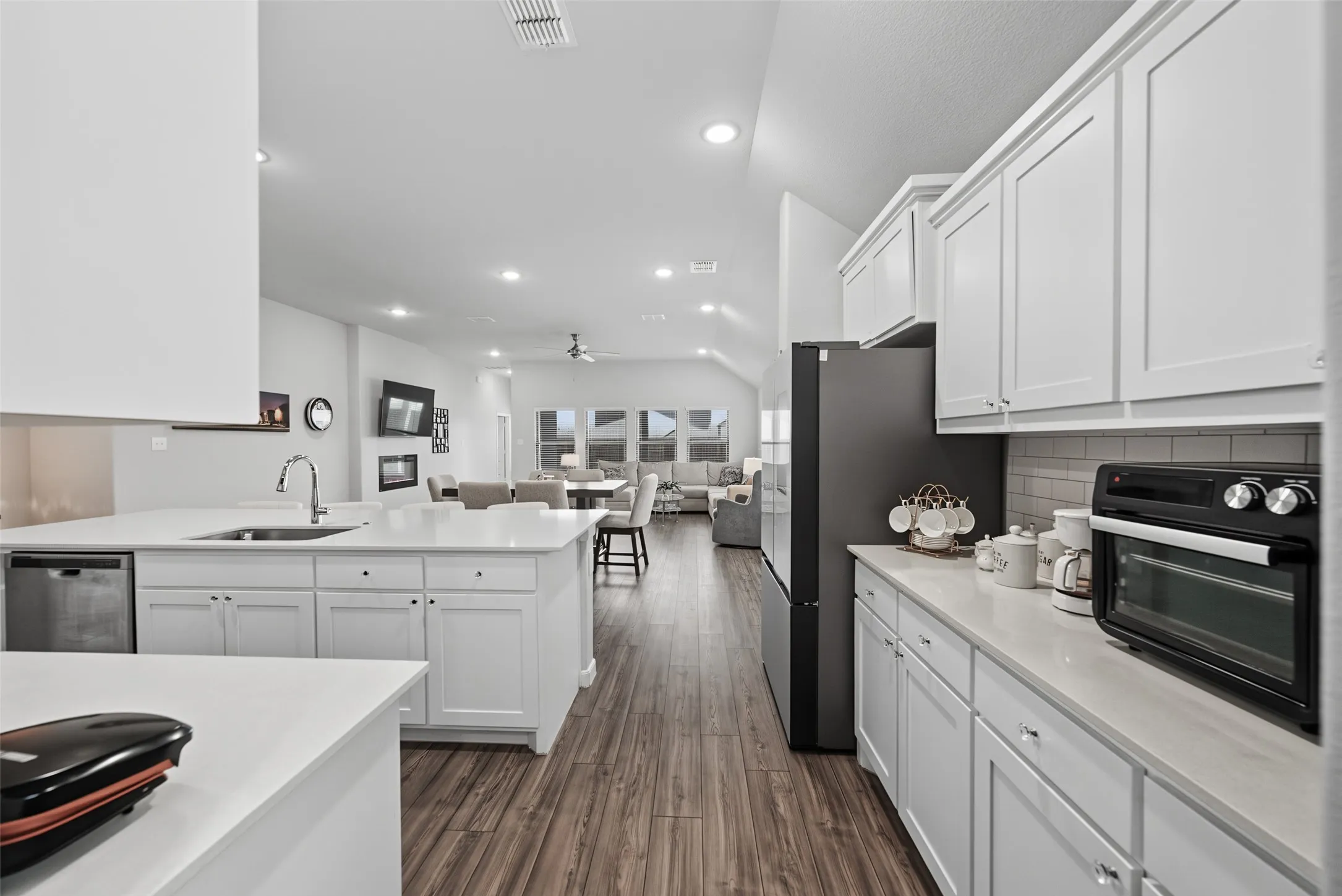 Kitchen featuring white shaker cabinetry, light-toned countertops, a stainless steel sink, and wood-finish flooring