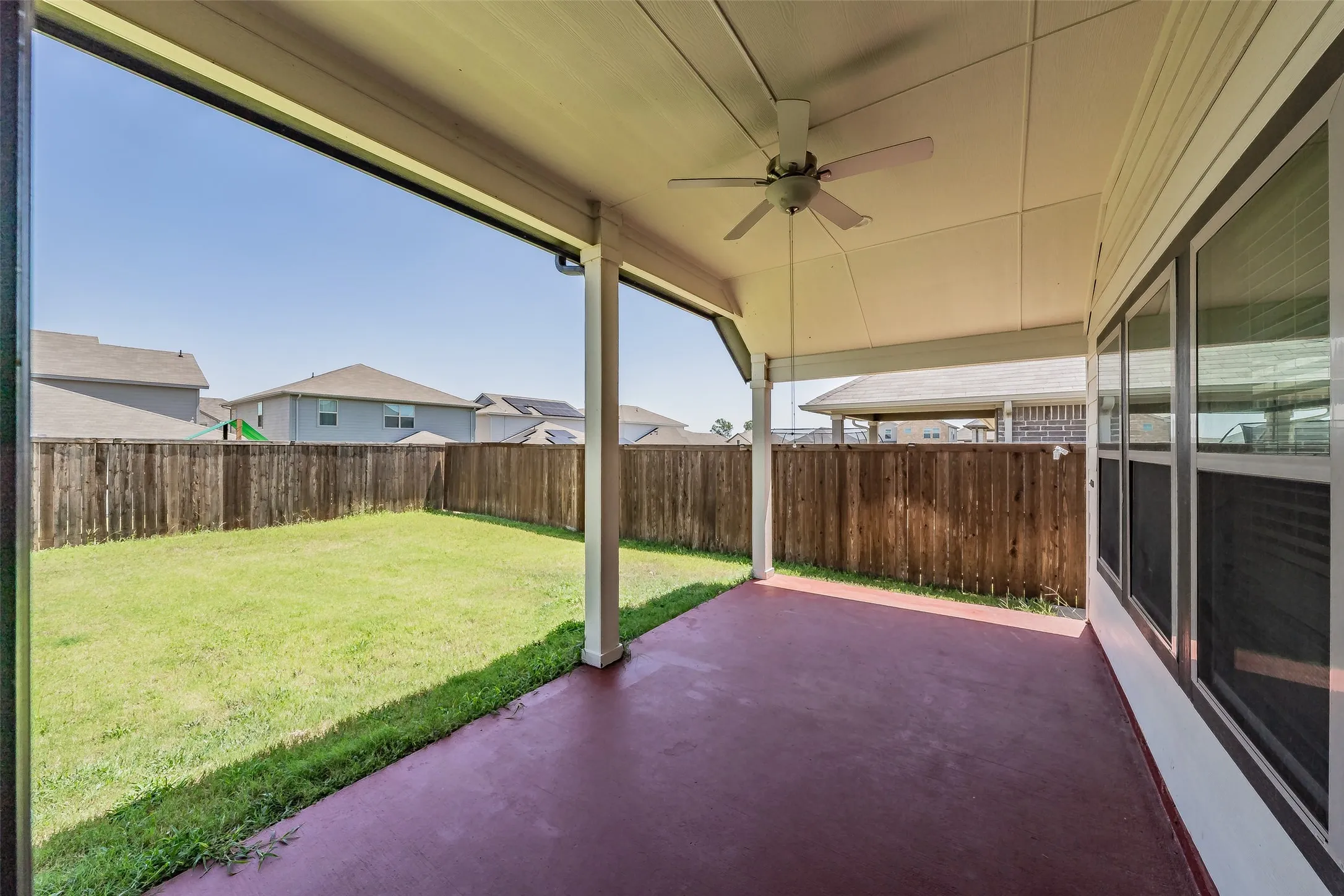 Covered patio with a ceiling fan, concrete flooring, and a fenced backyard with a grass lawn