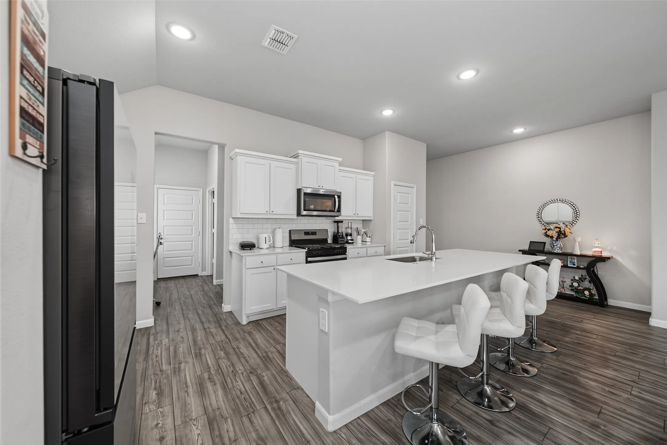 Kitchen featuring white cabinetry, a large center island with seating, stainless steel appliances, and wood-finish flooring