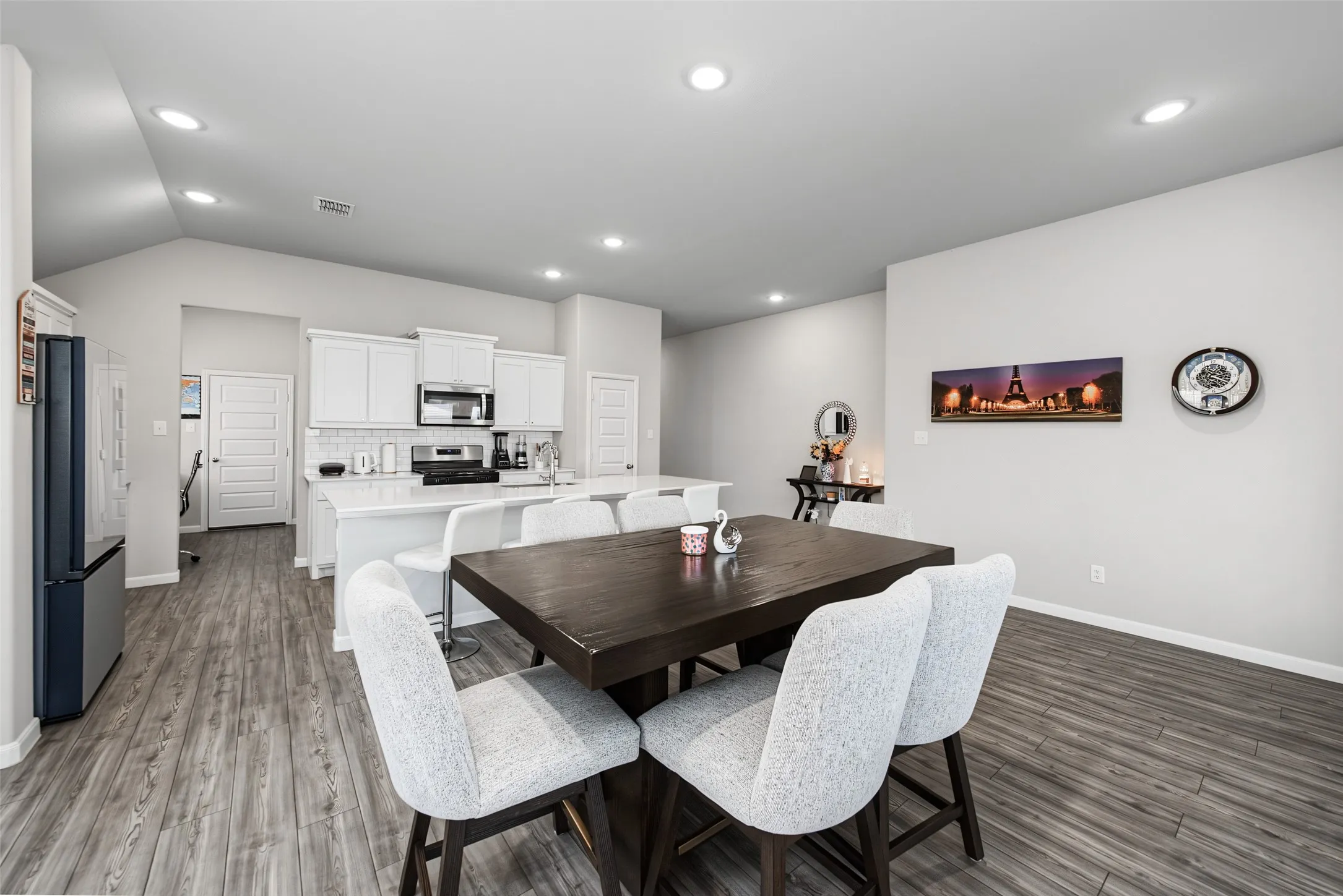 Open-concept living area featuring wood-finish flooring, recessed lighting, and vaulted ceilings