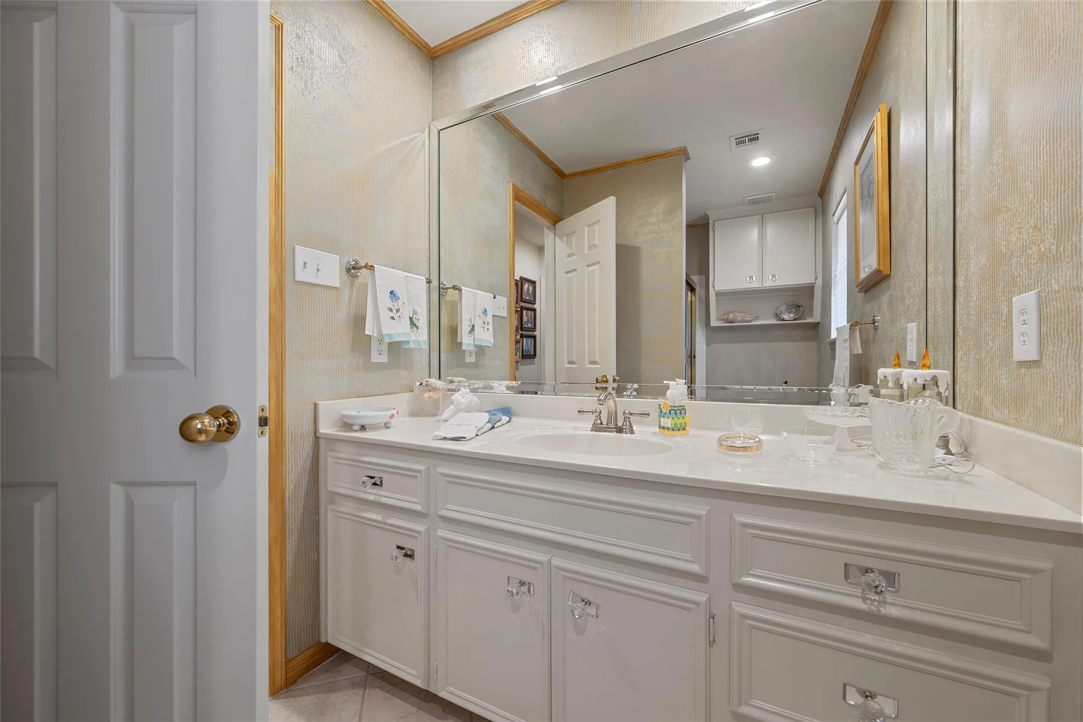 Double vanity featuring white cabinetry with decorative hardware, dual undermount sinks, and a light-toned countertop
