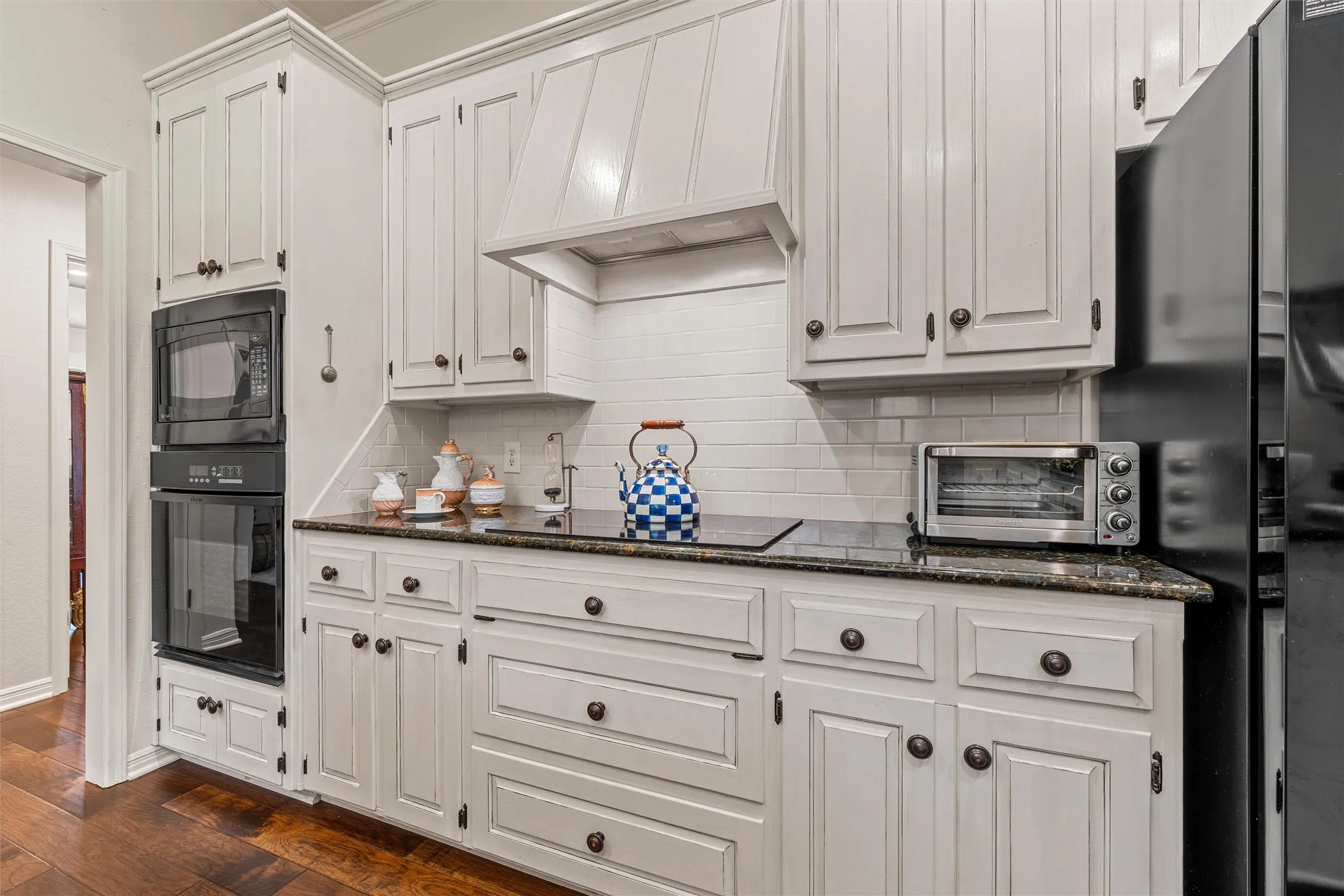 Kitchen featuring light-toned cabinetry, built-in microwave, dark cooktop, and a matching refrigerator