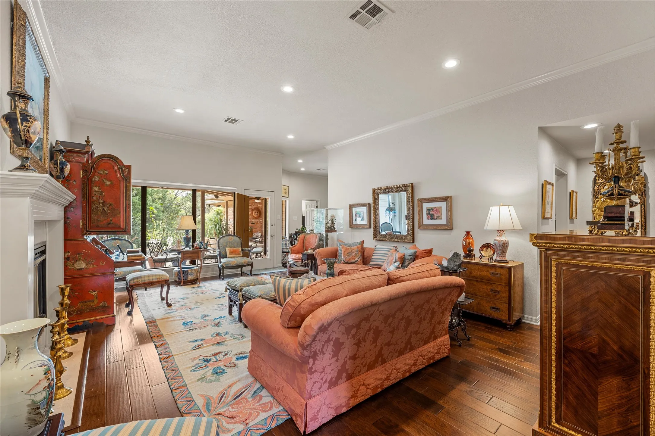 Spacious living area featuring polished wood-finish flooring, a white mantel fireplace, and a large picture window