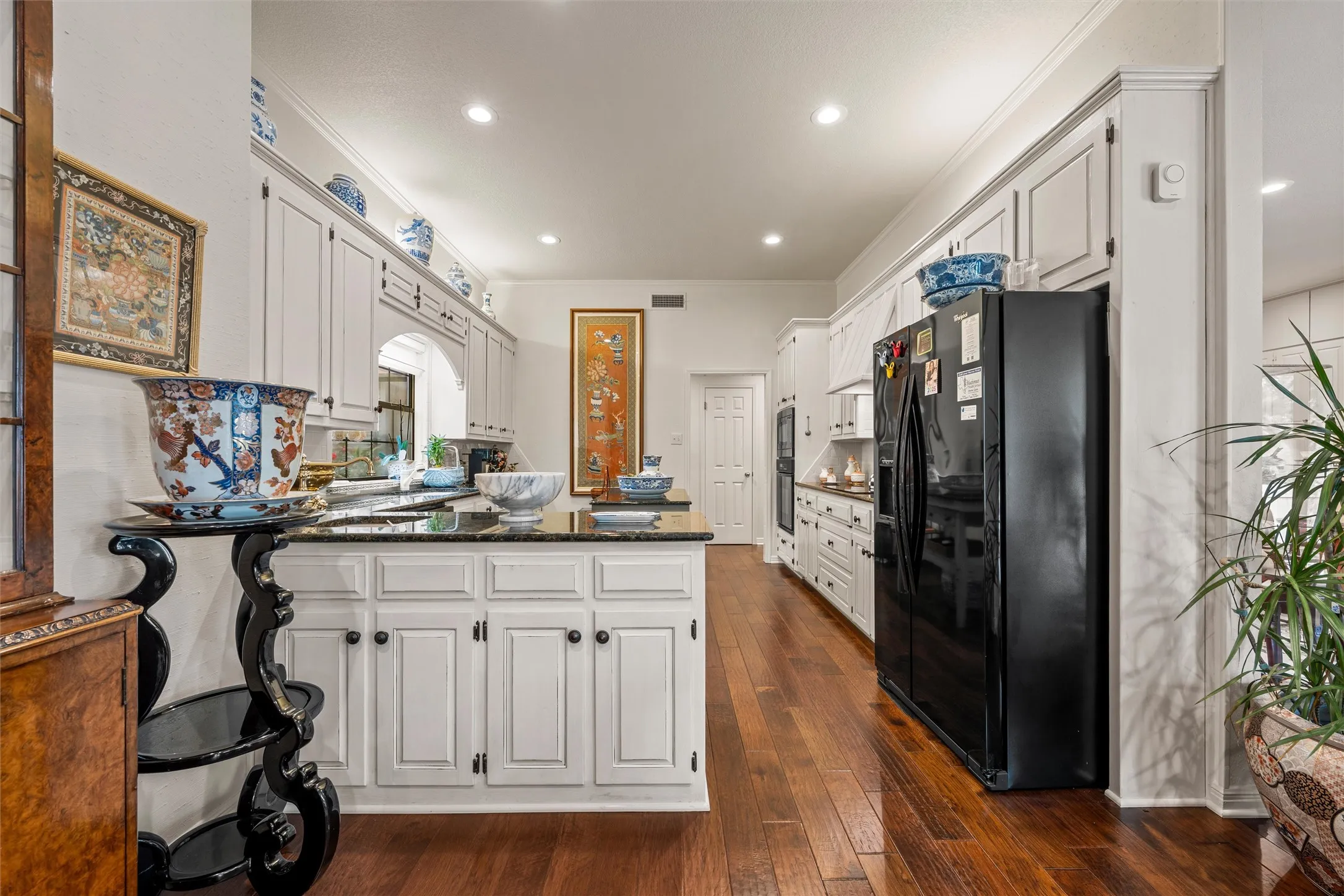 Spacious kitchen featuring wood-finish flooring, white cabinetry with black hardware, and dark​​‌​​​​‌​​‌‌​‌‌​​​‌‌​‌​‌​‌​​​‌​​ countertops