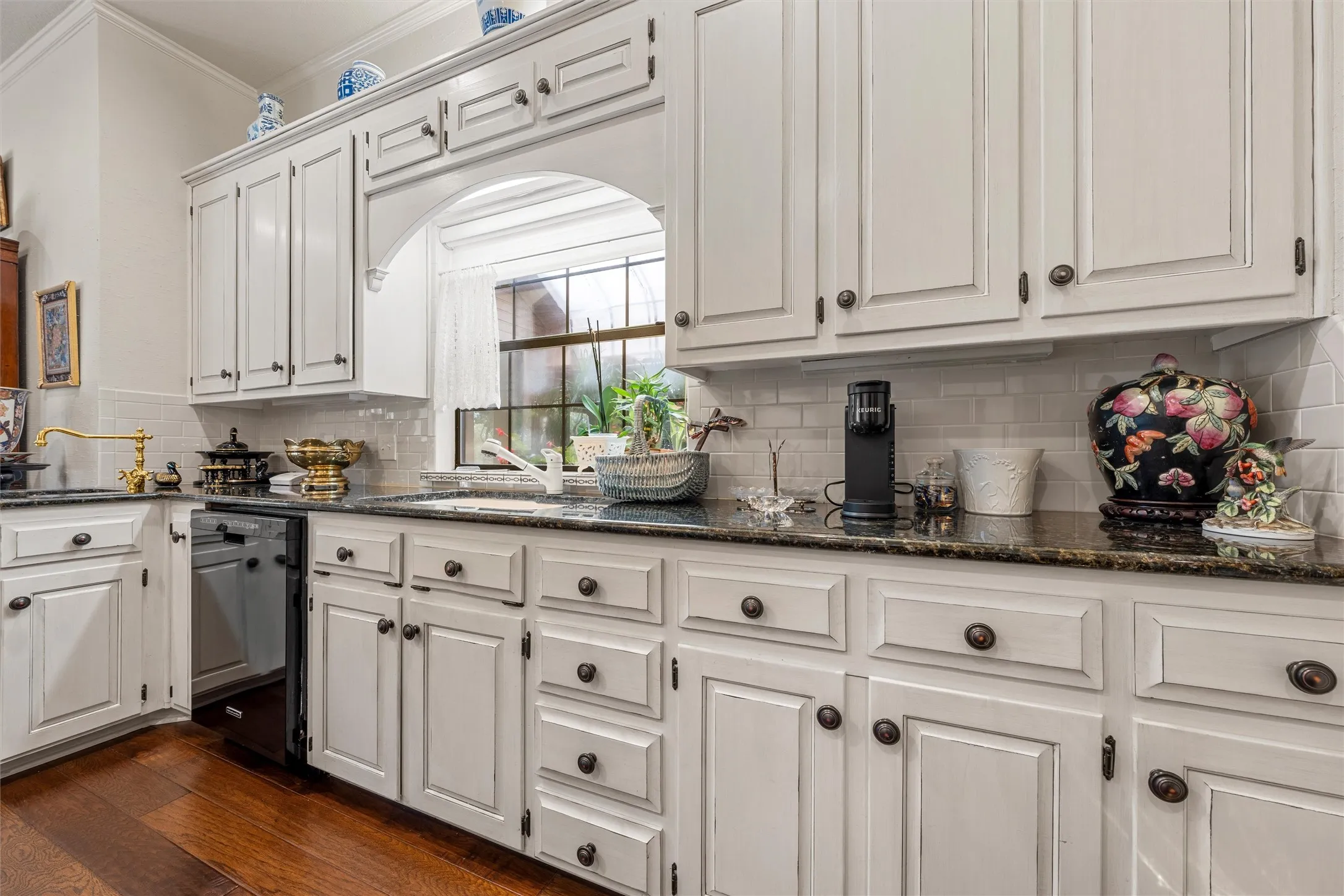 Kitchen featuring white cabinetry, dark stone countertops, a subway tile backsplash, and wood-finish flooring