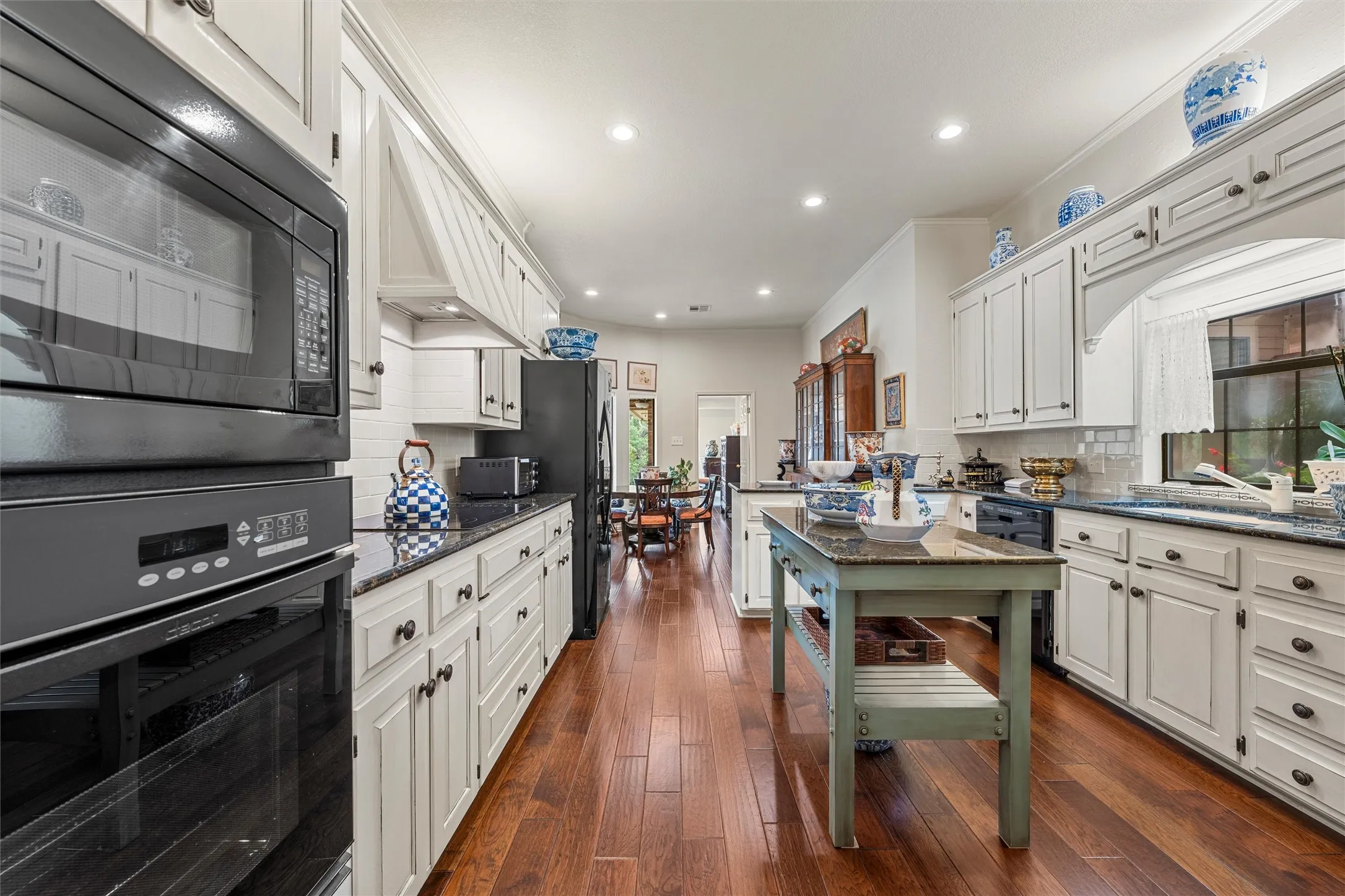 Kitchen featuring white cabinetry, wood-finish flooring, recessed lighting, dark countertops, and built-in appliances