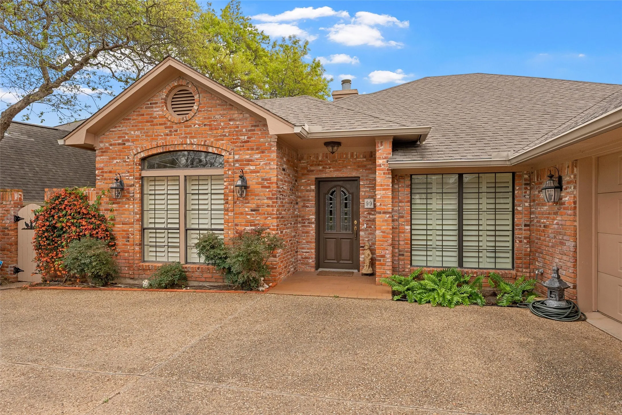 Brick exterior residence featuring an arched window, decorative shutters, and a covered entry