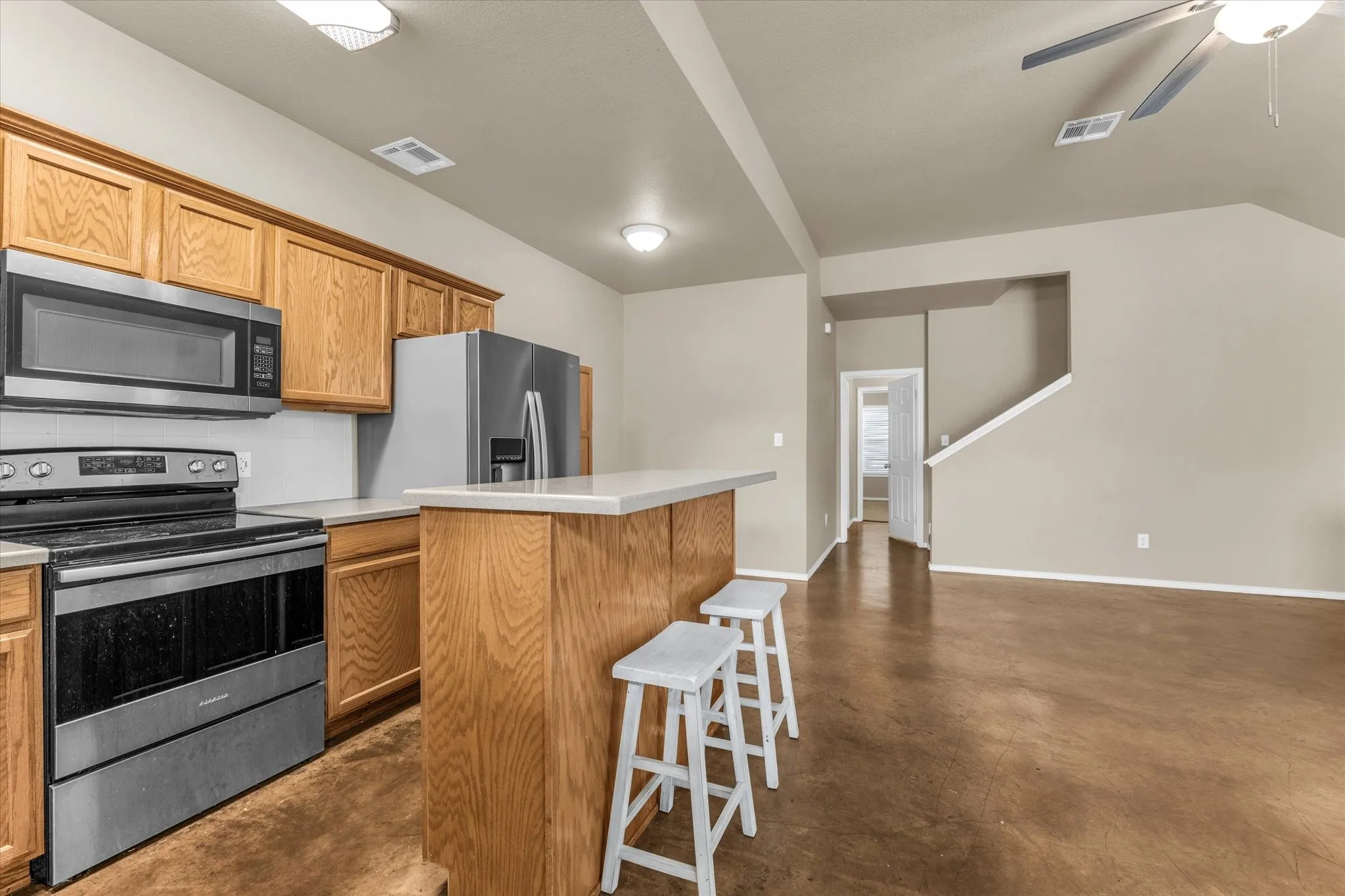 Kitchen featuring stainless steel appliances, wood-finish cabinetry, and a breakfast bar with solid surface countertops