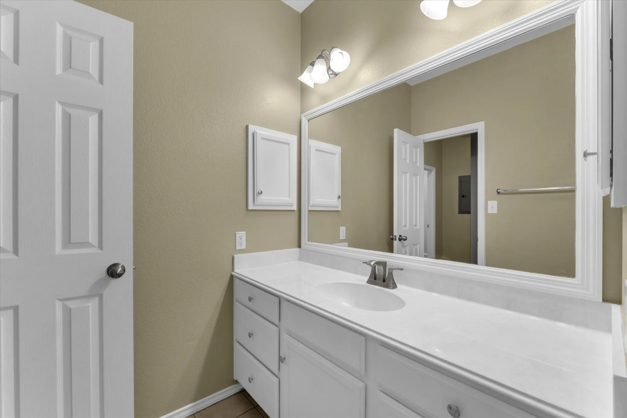 Bathroom vanity featuring a single basin, white countertop, and white cabinetry with brushed nickel hardware