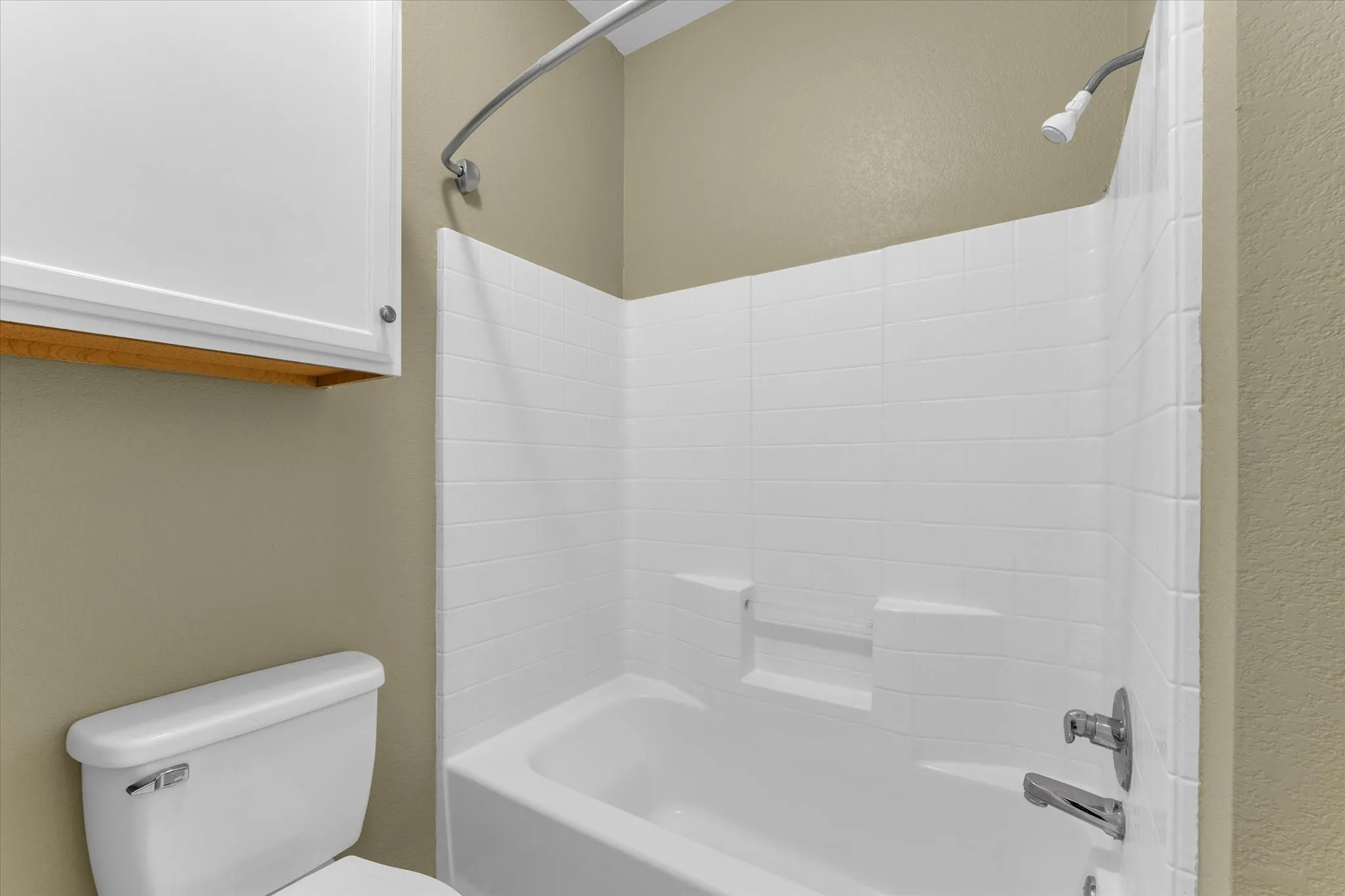 White subway tile-patterned shower surround with integrated shelving and chrome fixtures